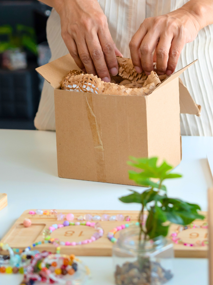 Small creative business owner unpacking product orders surrounded by colorful beaded jewelry — signs you need a creative business audit