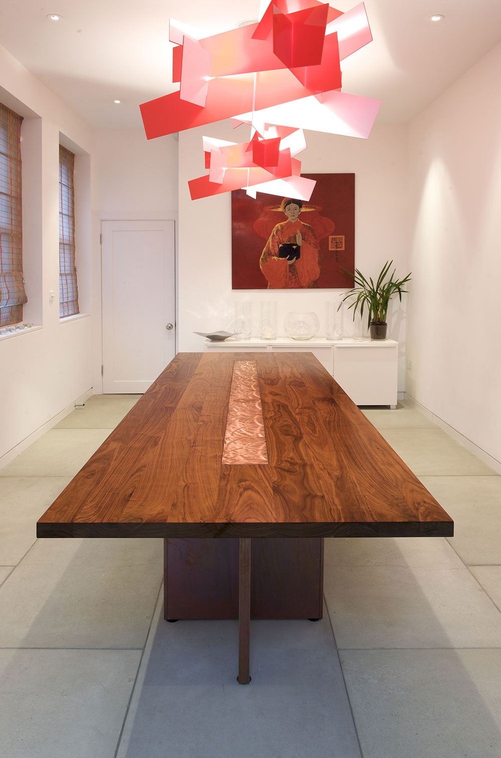 An integrated brushed copper trivet offers a warm looking, heat-proof surface on this solid walnut dining table.