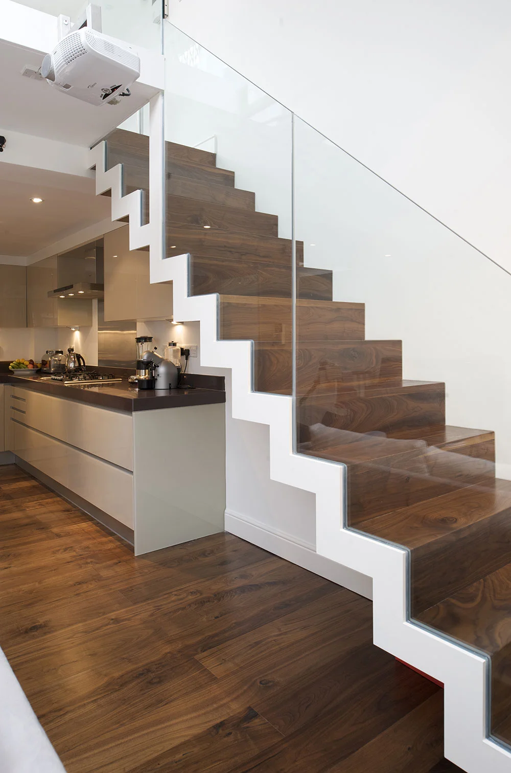 This floating staircase leading to a mezzanine level is constructed from lazer cut steel and solid walnut treads.