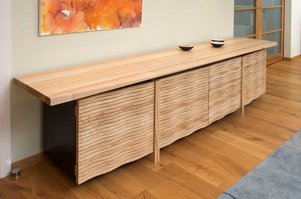The design for this sideboard is inspired by the sand dunes on a beach near to the client's home in Devon. The tactile frontage exploits the subtle colour differences between olive ash and wild ash, and has inspired a number of further 'wavy' commissions.