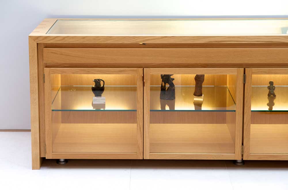 This solid oak display cabinet with underlit glass shelving and lockable doors is designed for a unique private collection of Roman artifacts.
