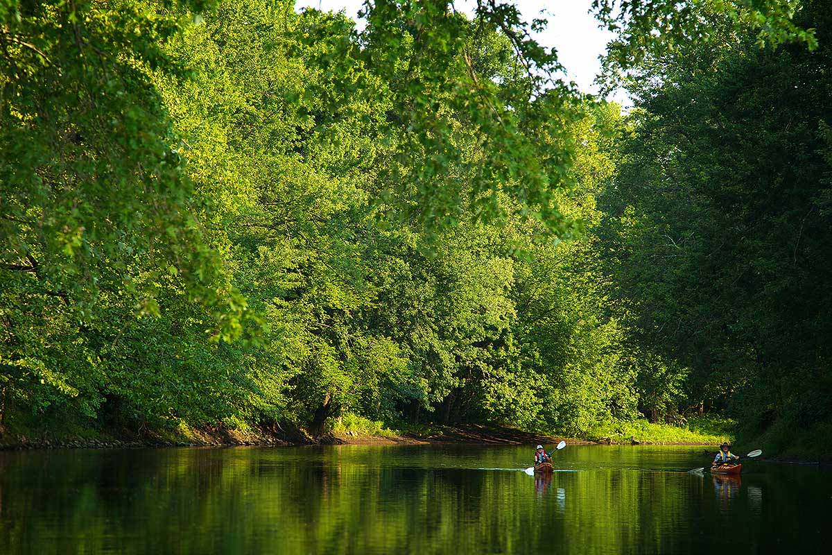 Two kayakers float down a river in Connecticut.