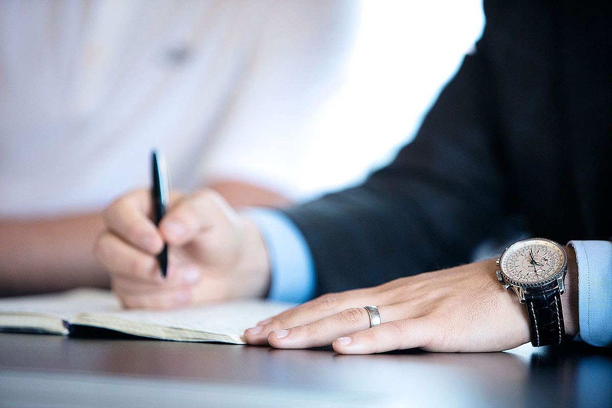 Stock image of a man writing in a meeting.