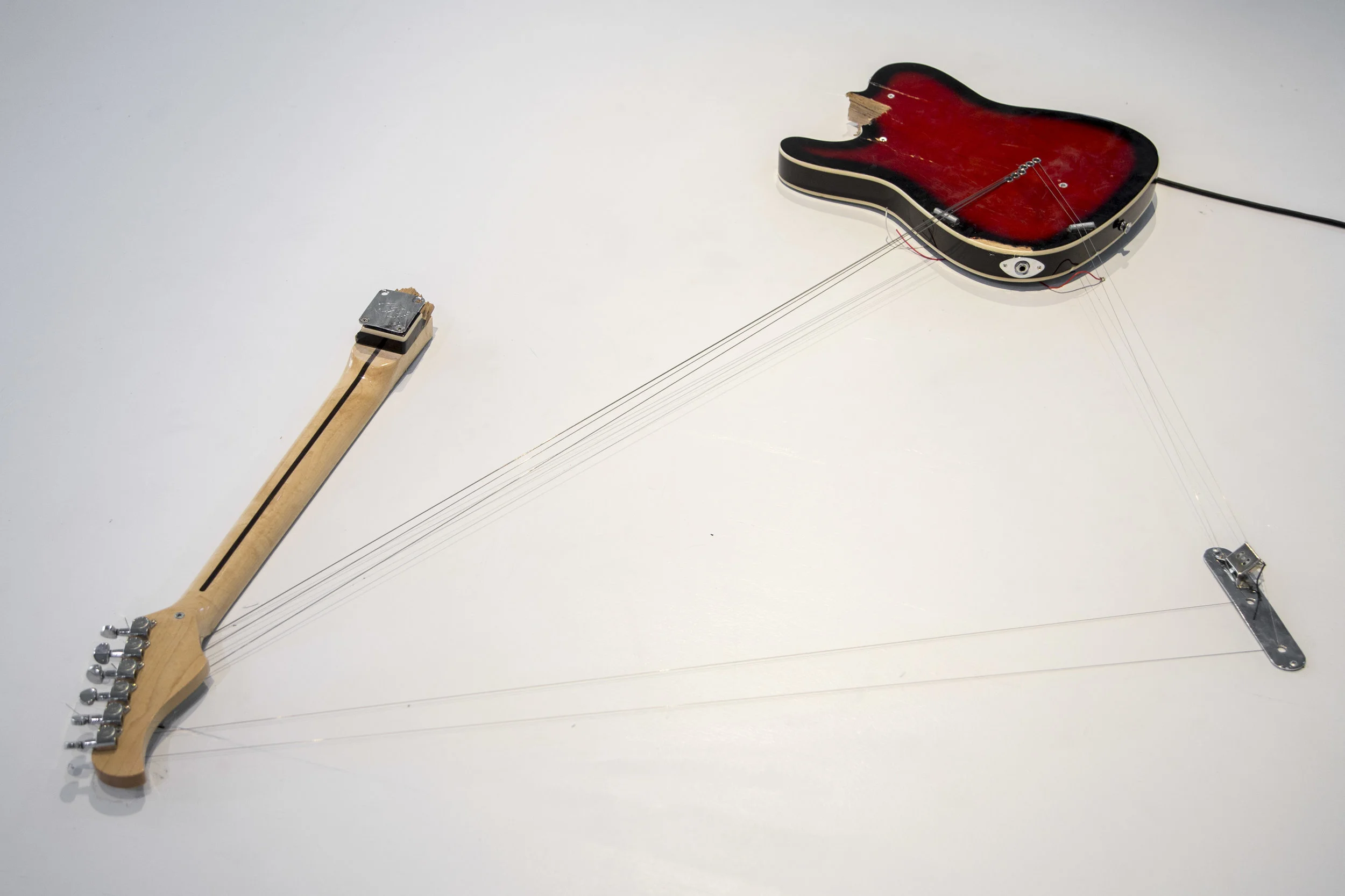 Melody of Certain Damage #6, 2018, broken electric guitar, strings, microphone, screws and amplifier, 57” x 39” x 2.5”. Image by Loló Bonfanti