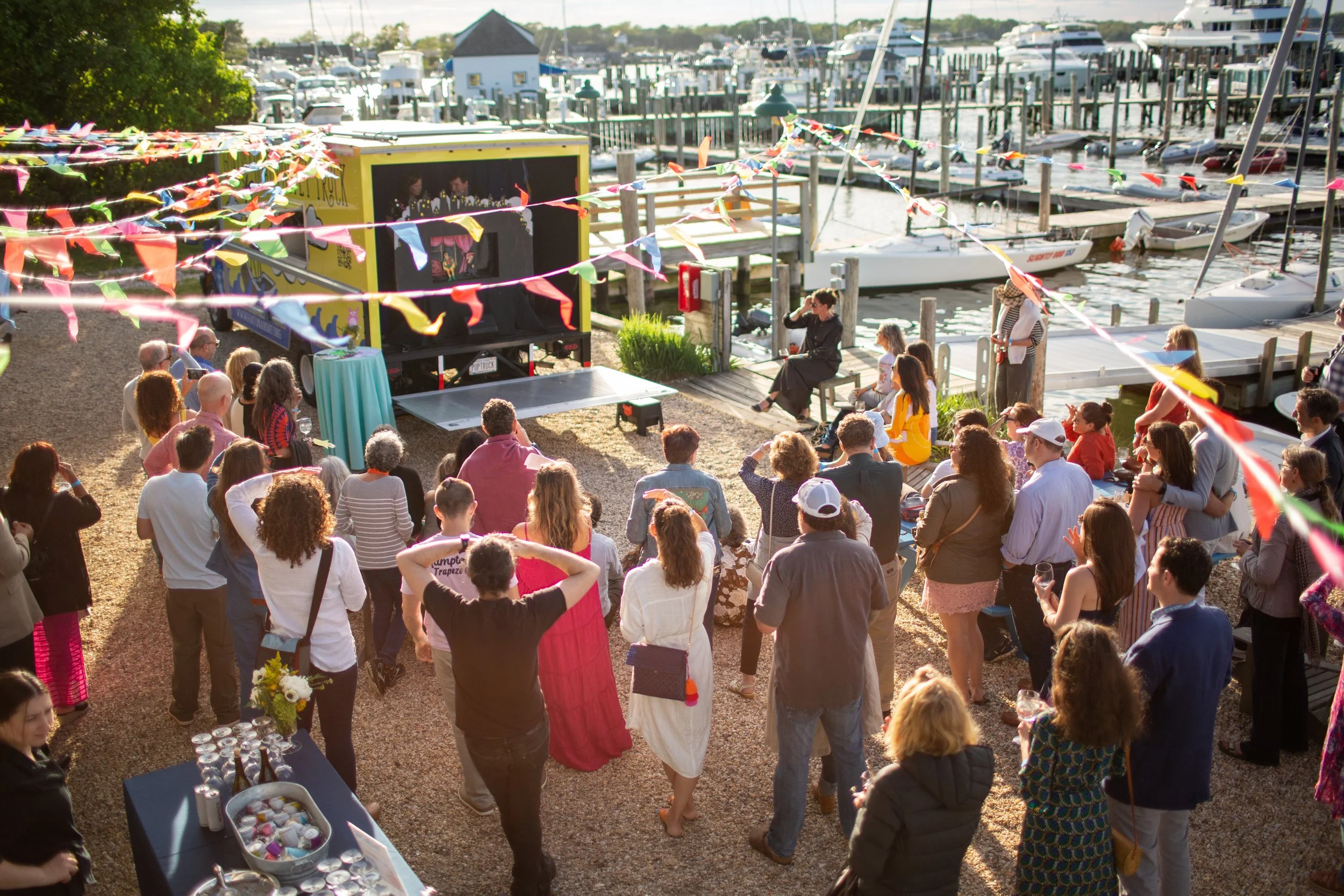 crowd gathered outdoors to watch a puppet show on the Goat on a Boat Puppet Truck