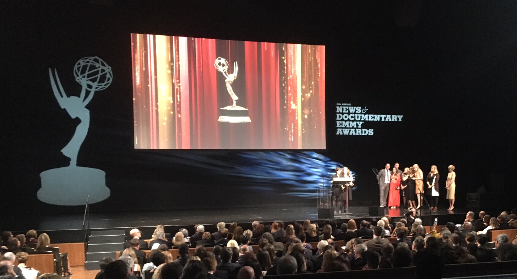 THE WHOLE TEAM ON STAGE WITH AS KIRSTEN ACCEPTS THE EMMY