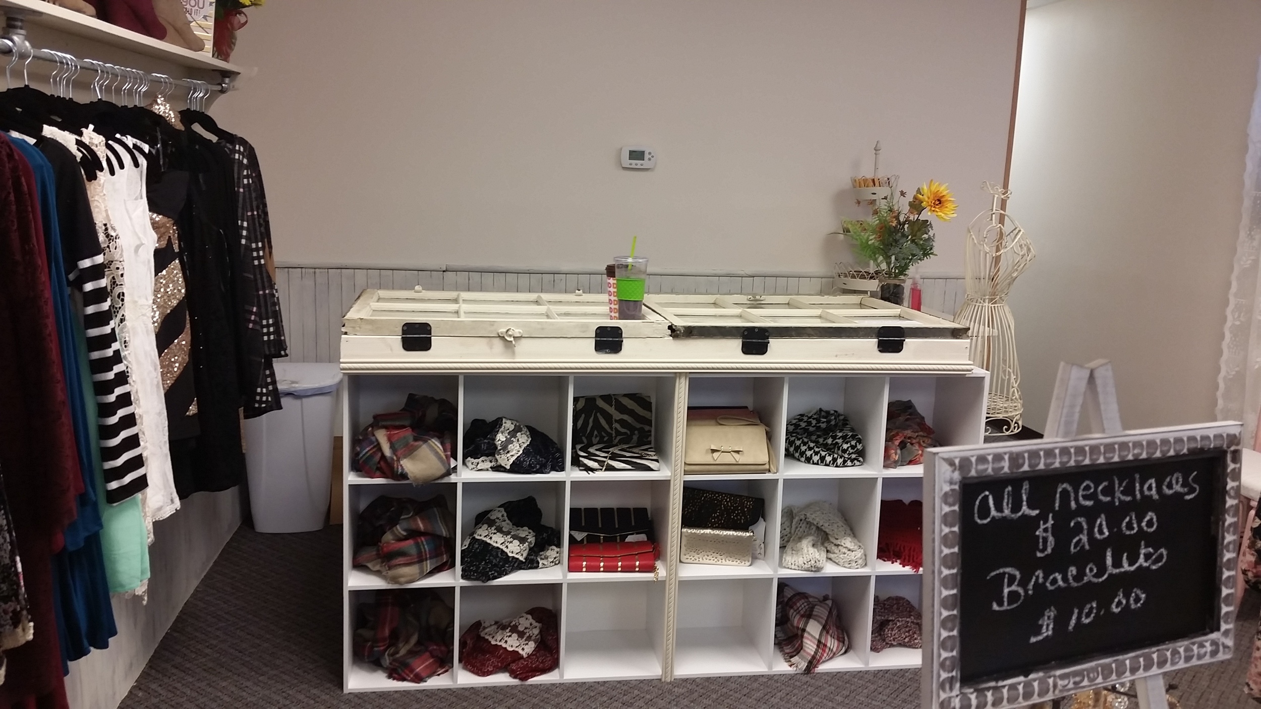 A case fashioned from repurposed windows makes a lit display counter for jewelry atop back to back cubbies that create storage on both sides.