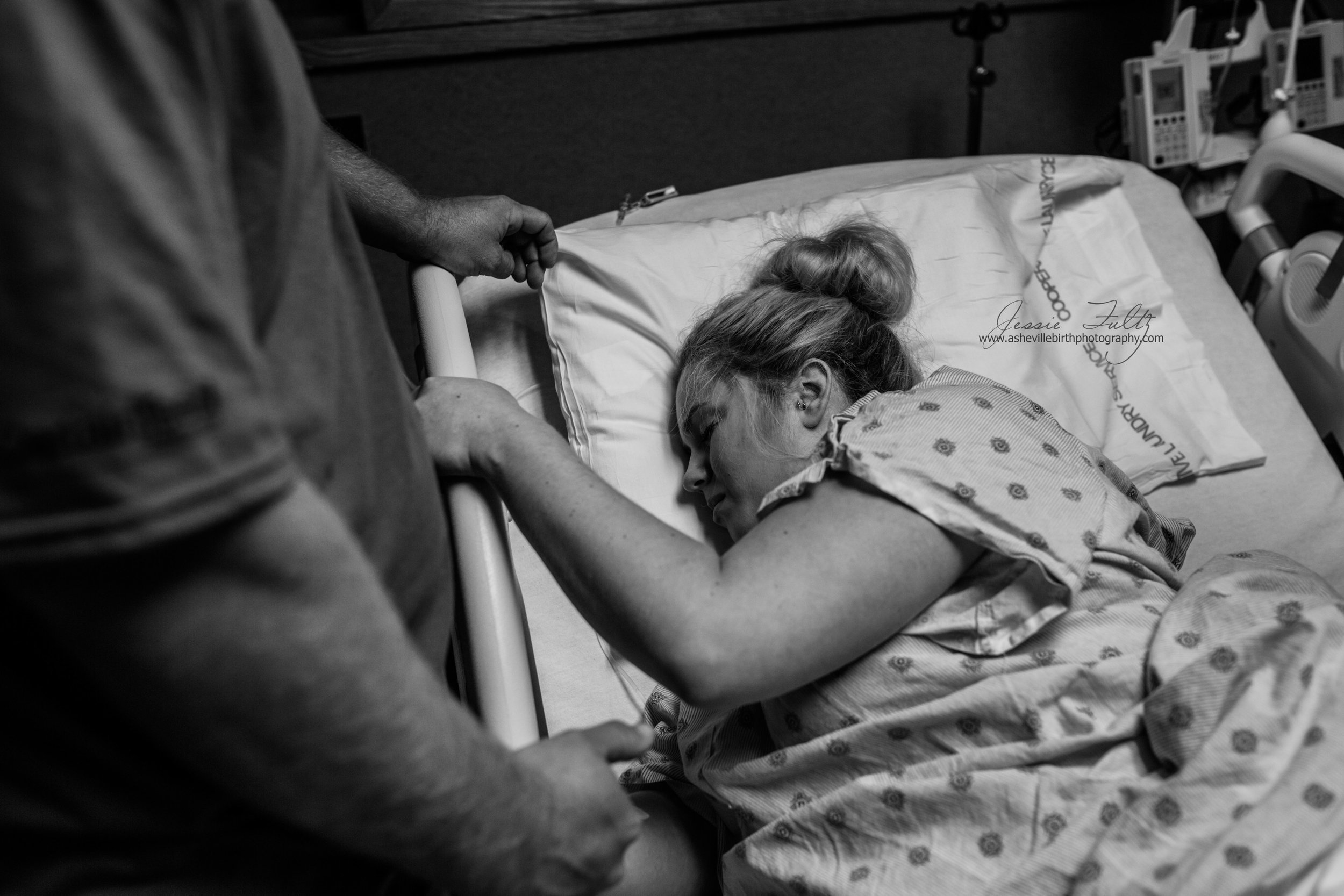 a laboring woman grips the side of her hospital bed during a contraction