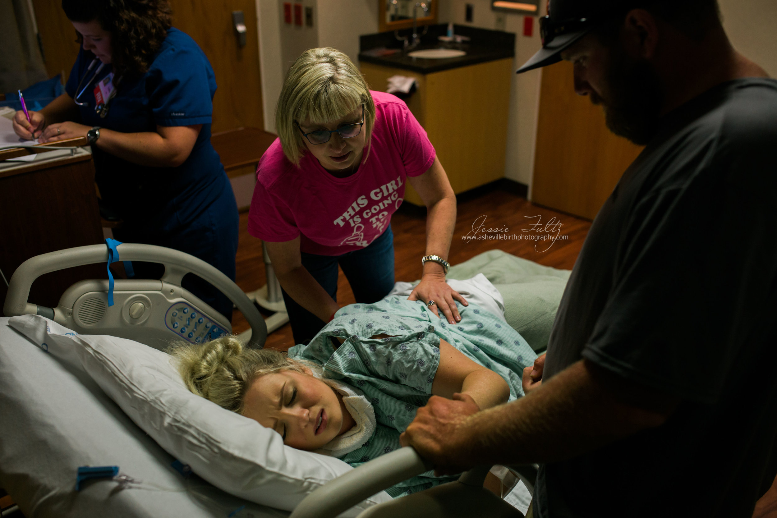 a mother rubs her laboring daughter's back during a contraction