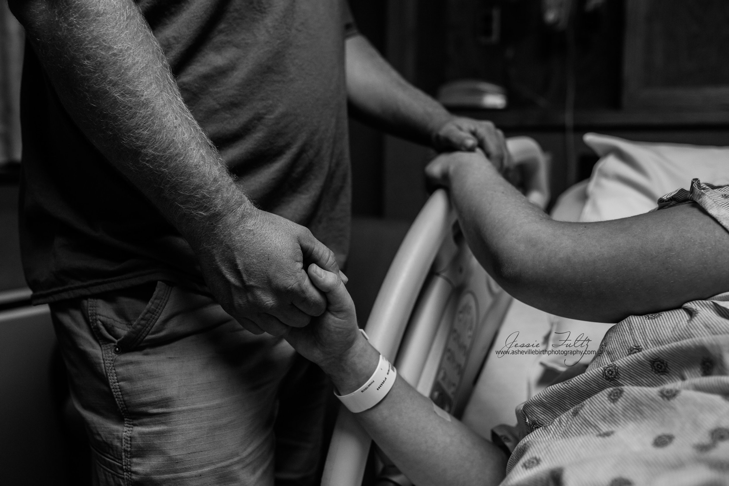 a close-up of a husband and wife holding hands during labor