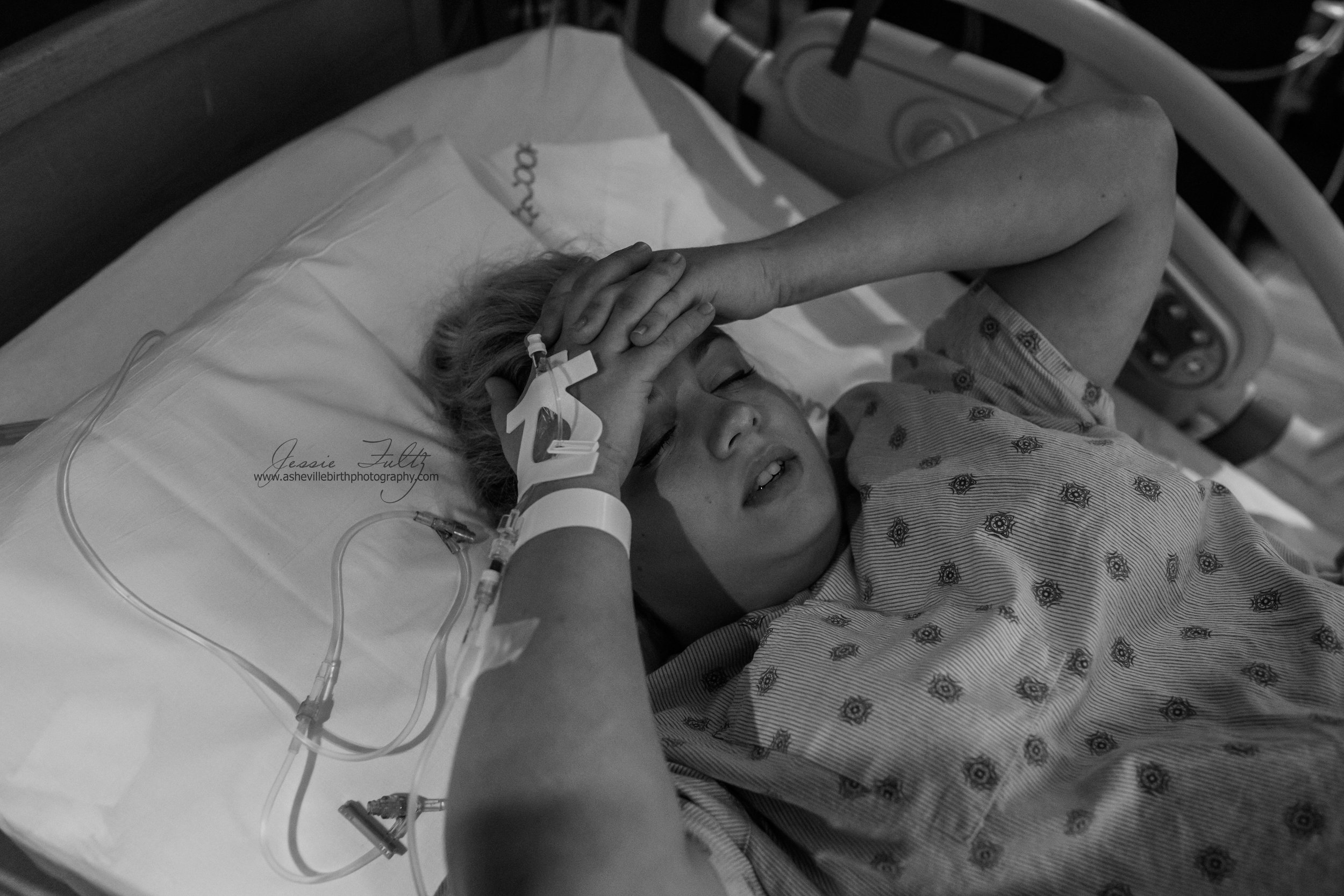 a laboring woman clasping her hands and resting them on her forehead during a contraction