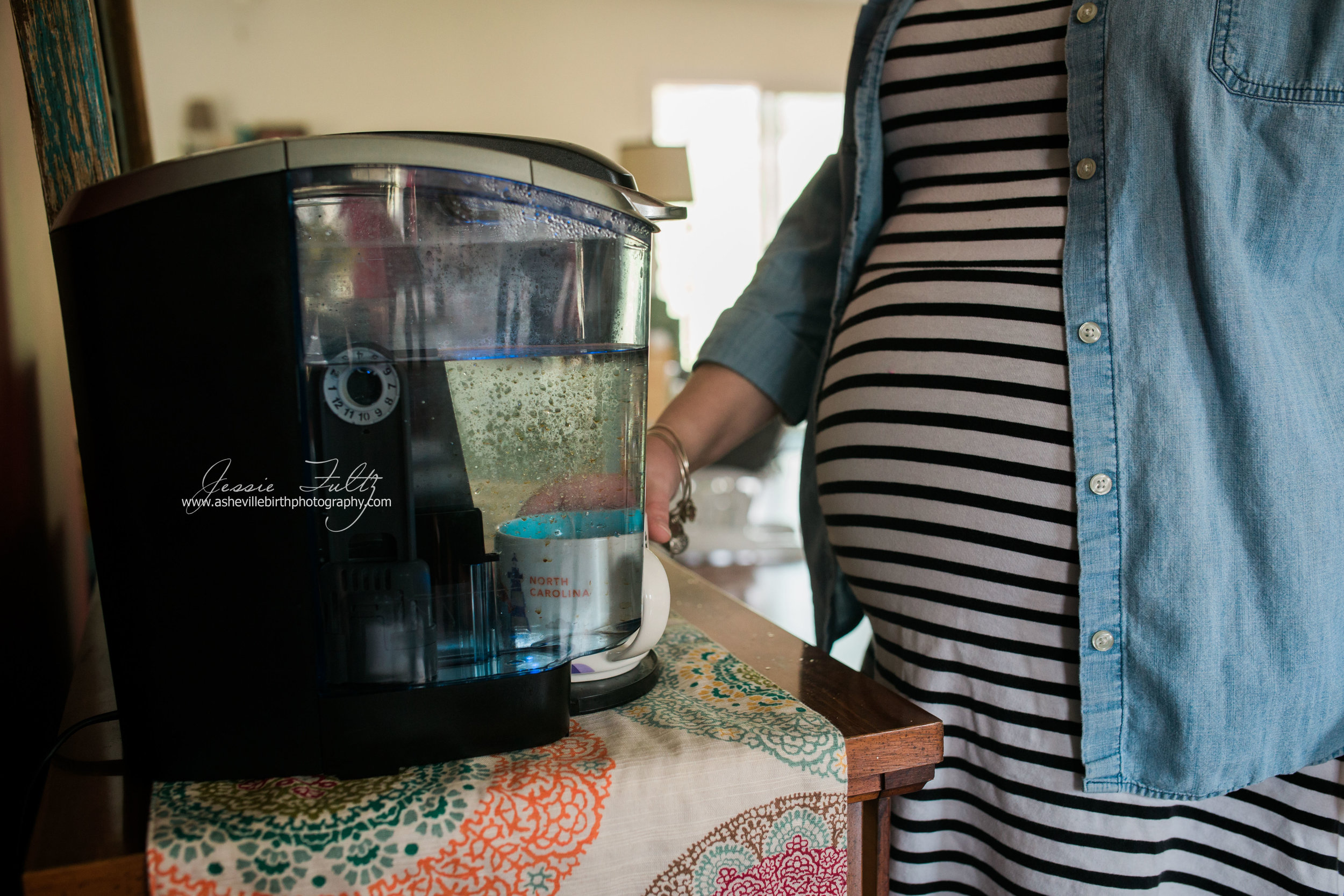 close-up of a pregnant belly in striped dress and a keurig machine with a North Carolina coffee cup