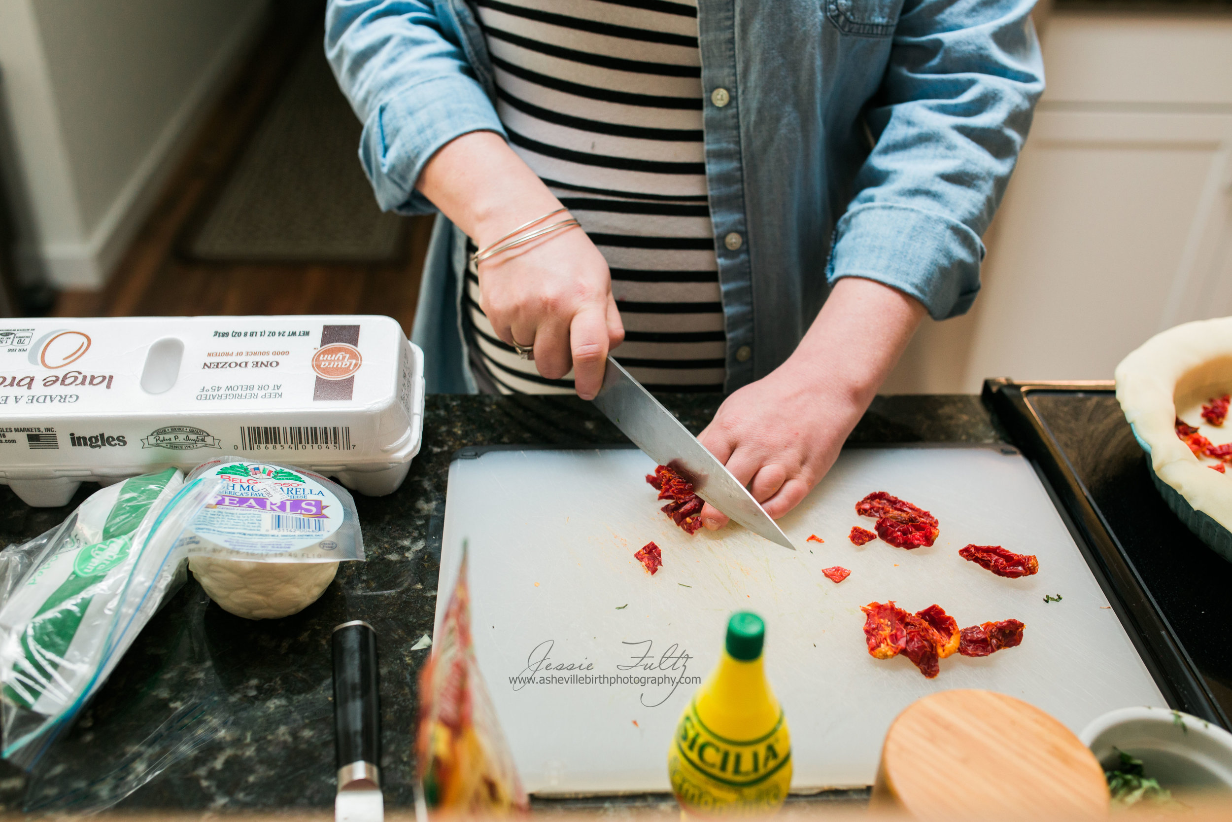 close-up picture of a pregnant woman chopping sun-dried tomatoes on a white cutting board