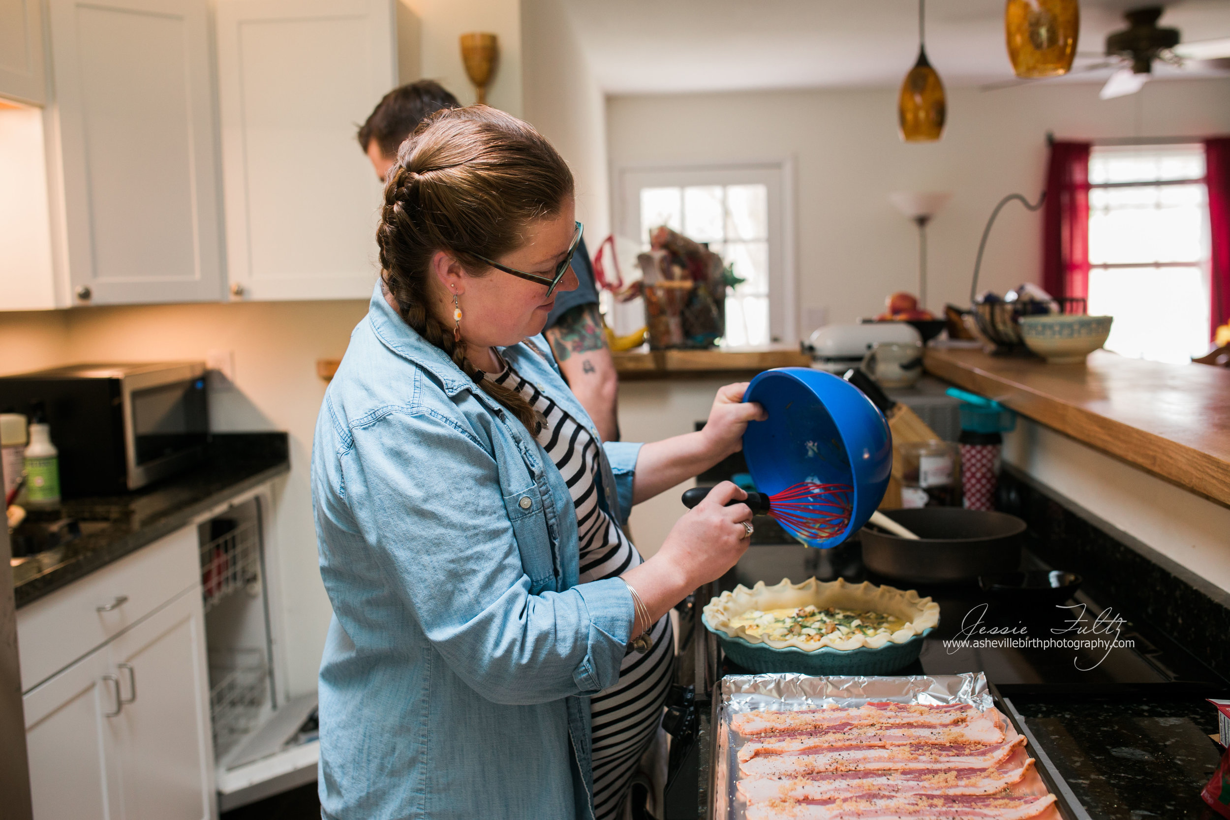 pregnant woman in striped dress pouring quiche mixture from a a blue bowl using a red whisk