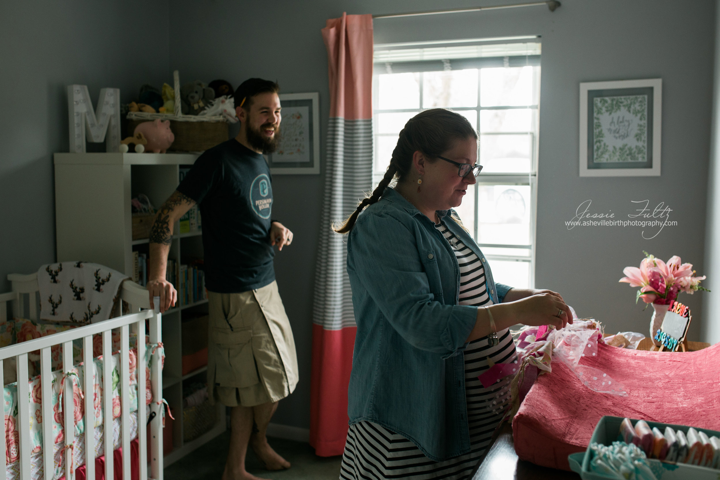 pregnant woman and husband standing in nursery laughing