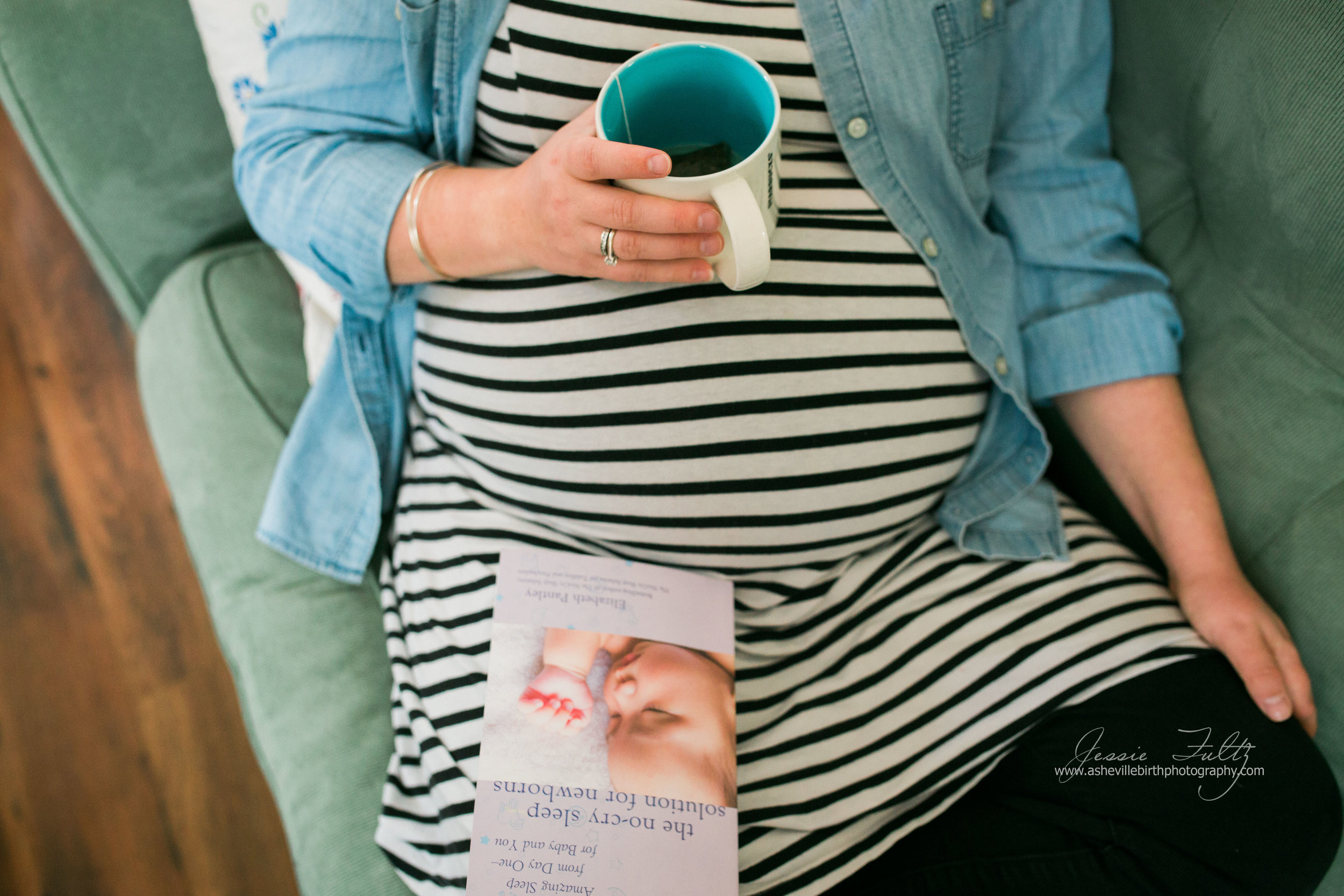 close-up picture of a pregnant woman resting her coffee mug on her belly and a book called "The No-cry Sleep Solution for Newborns" in her lap