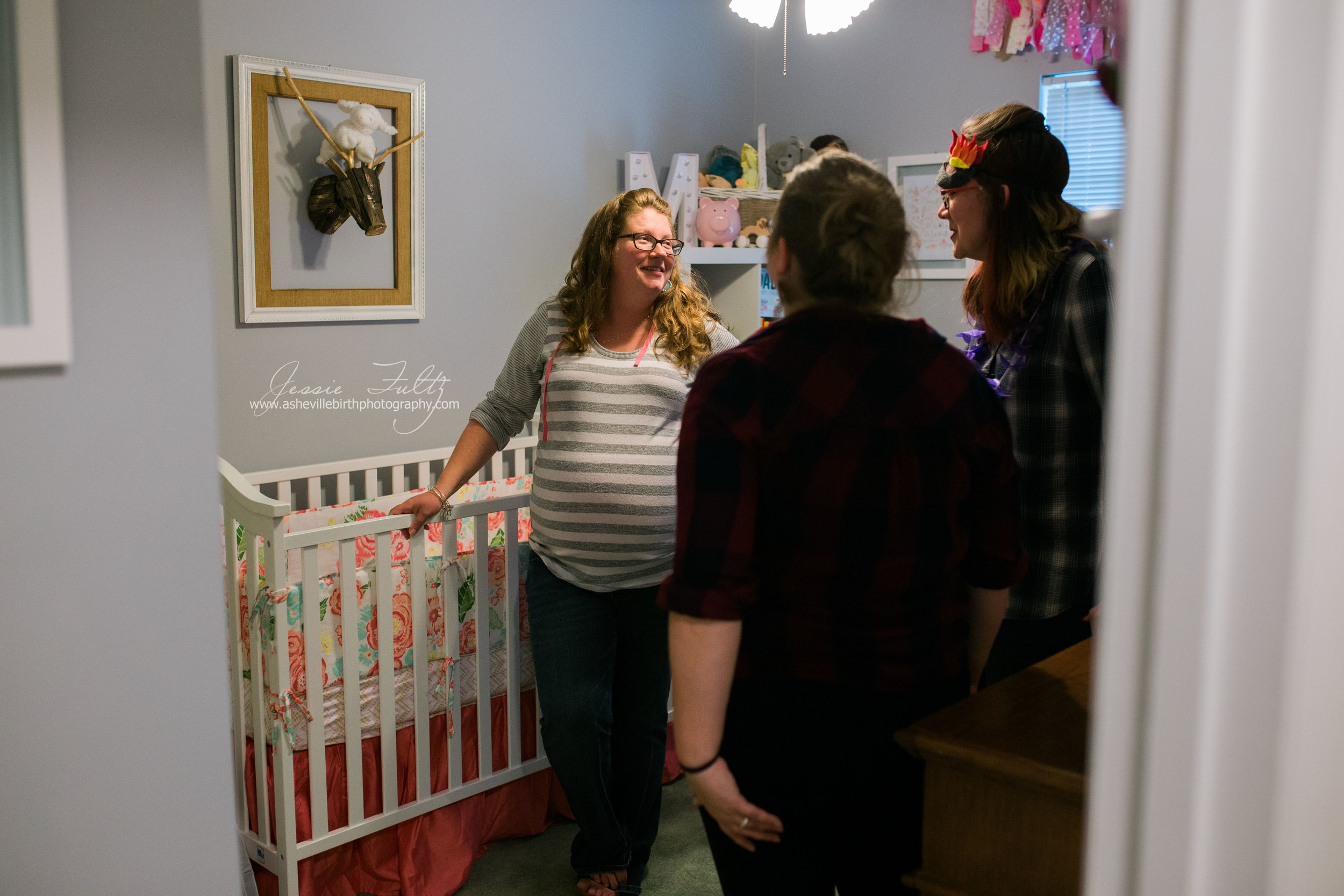 a pregnant woman standing in her baby's nursery talking with a few friends