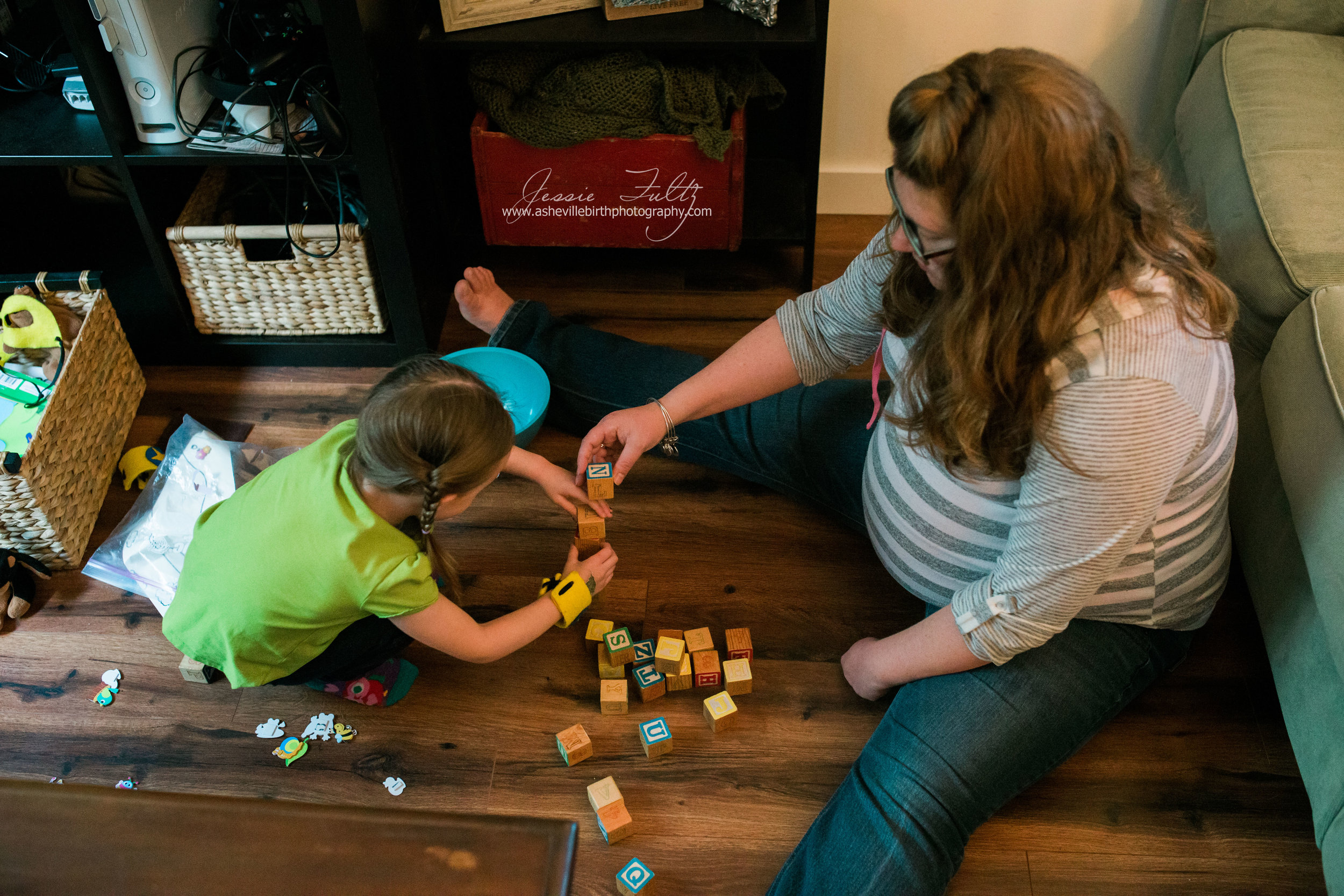 a pregnant woman and young girl using letter blocks to build a tower