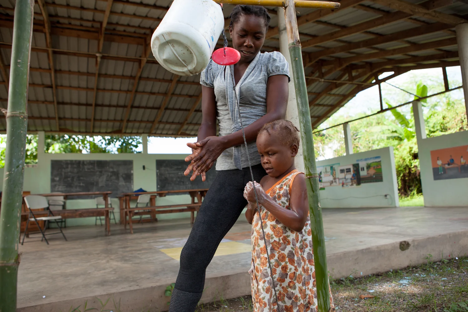 Caregiver at Second Mile’s Rehabilitation Center models hand hygiene for her young sister.