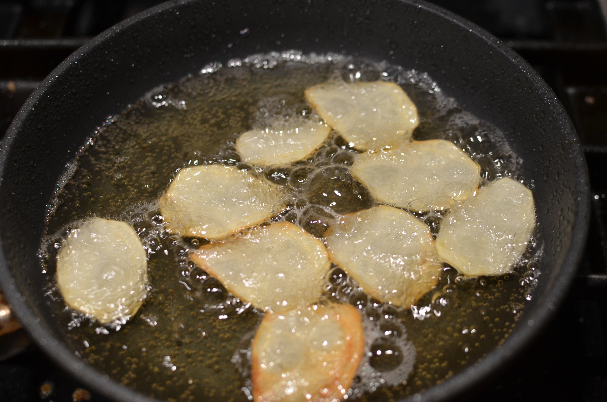Heat about an inch of oil in a good quality nonstick pan. I'm using my favorite nonstick by Swiss Diamond - it can hold up to the heat and clean up is a breeze. Working in small batches, fry a few chips at a time until the edges begin to curl and turn golden brown, then flip .