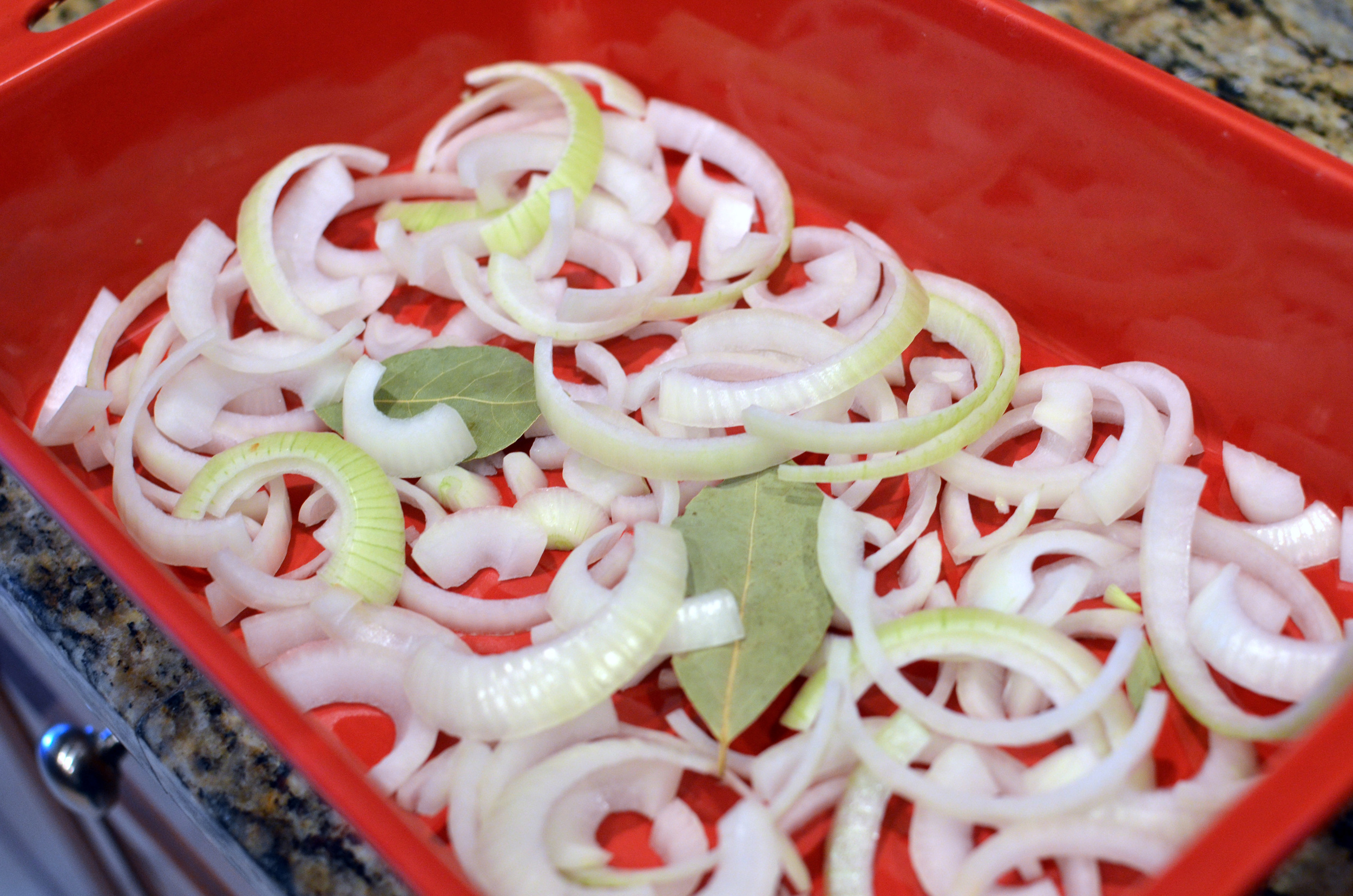 Layer onions and bay leaves in the bottom of a roasting pan; add 1 cup of water.