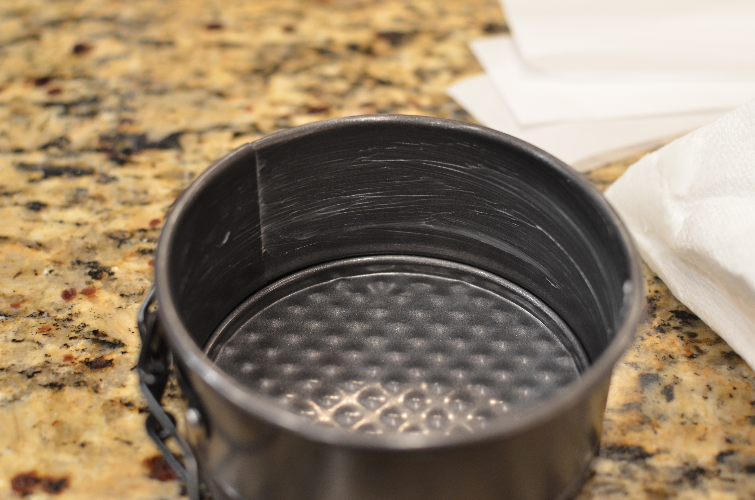 Use shortening to grease the sides of the pan only (do not grease the bottom of the pan). Press the parchment against the greased sides of the pan. Use a dab of shortening to glue the overlapping parchment ends together.