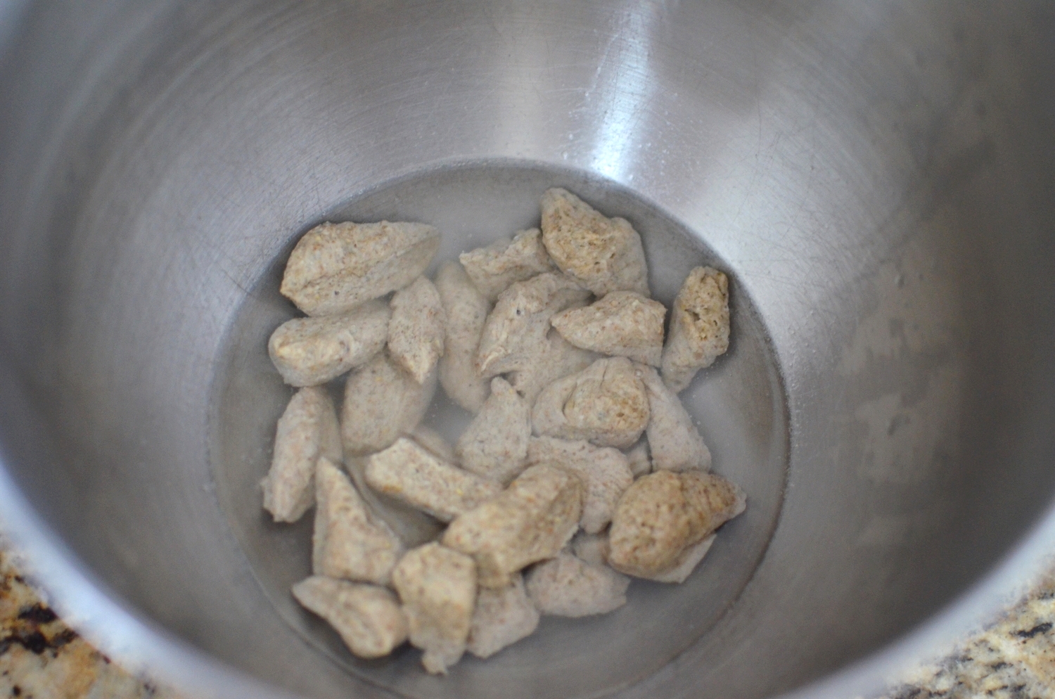 Okay, now for the fun part. Place room temperature water in the bowl of a stand mixer. Using sharp scissors, cut the biga into small pieces and place them in the bowl.