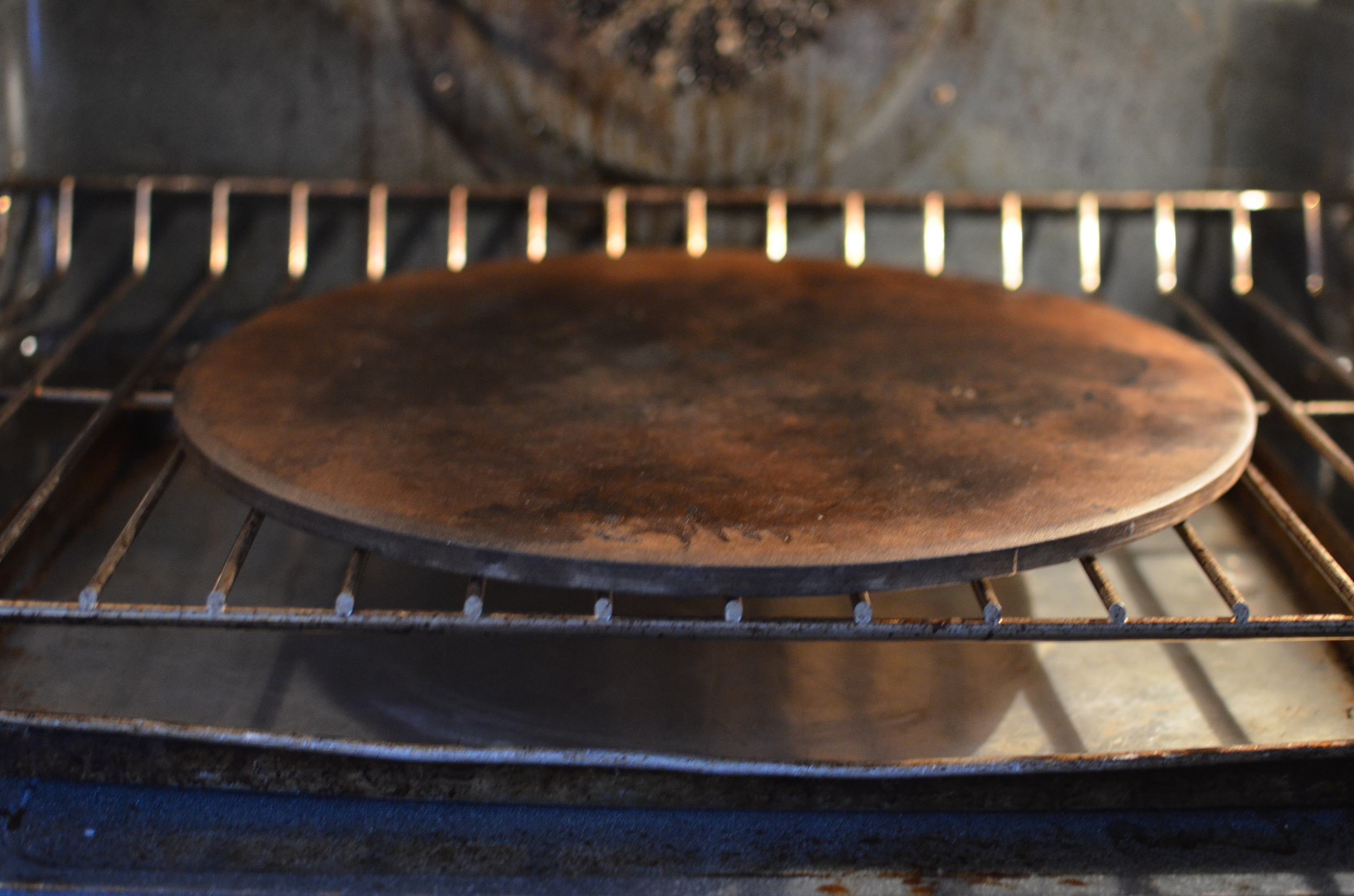 Place a baking stone on the bottom rack of the oven. Place a sheet pan or cast iron pan lined with foil on the oven floor. Crank the heat up to 450F for at least 45 minutes before baking. One word of caution here. The pan on the oven floor is going to take quite a bit of abuse. I chose to use my vegetable roasted pan. It's my "sacrificial" pan - the one that I don't mind how abused or burnt or bent or beat up it gets. It was a good choice on my part because throwing ice cubes on that 450F pan caused it to warp instantly. My cast iron skillets were too tall to fit under the baking rack so that wasn't an option. I might suggest getting a disposable foil pan or try making your own disposable pan out of a couple layers of heavy duty foil. 