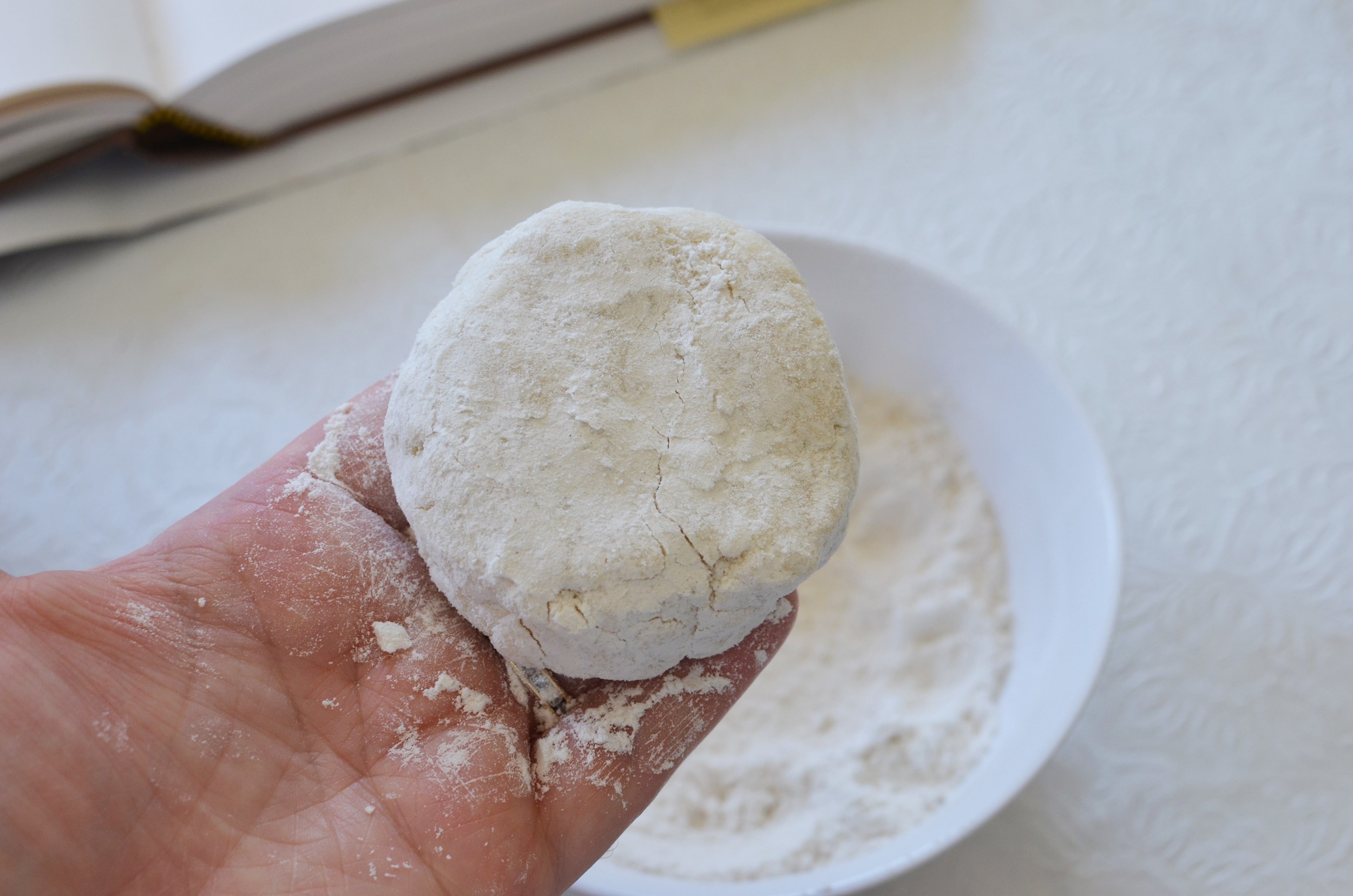 Plop each portion of biscuit dough in some flour to coat, then use your hands to shape them into a flat round.