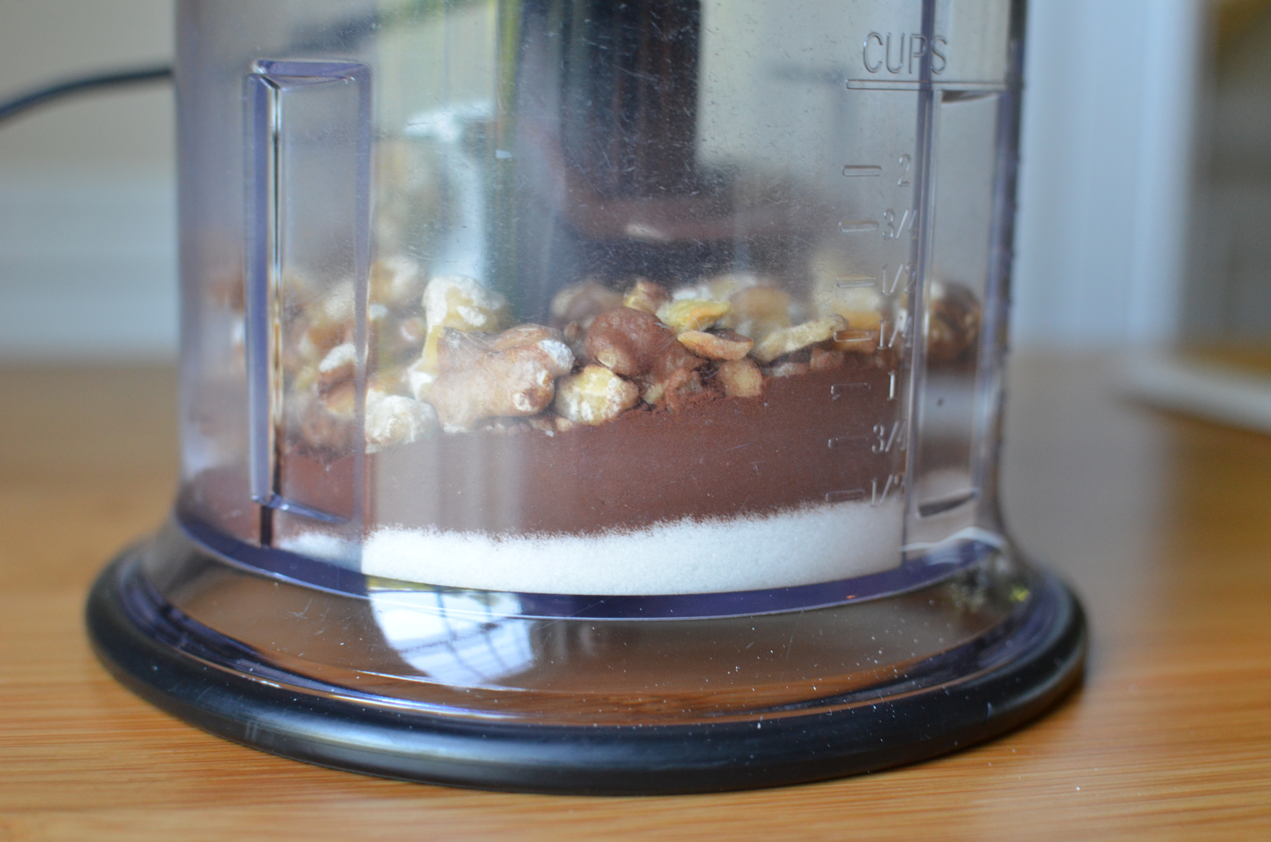 In the bowl of a smallish food processor, combine the nuts, confectioners sugar, cocoa powder, and granulated sugar. Normally I would suggest sifting the confectioners sugar and cocoa powder to eliminate lumps, but it's really not necessary in this case because the blades of the processor will obliterate them. 