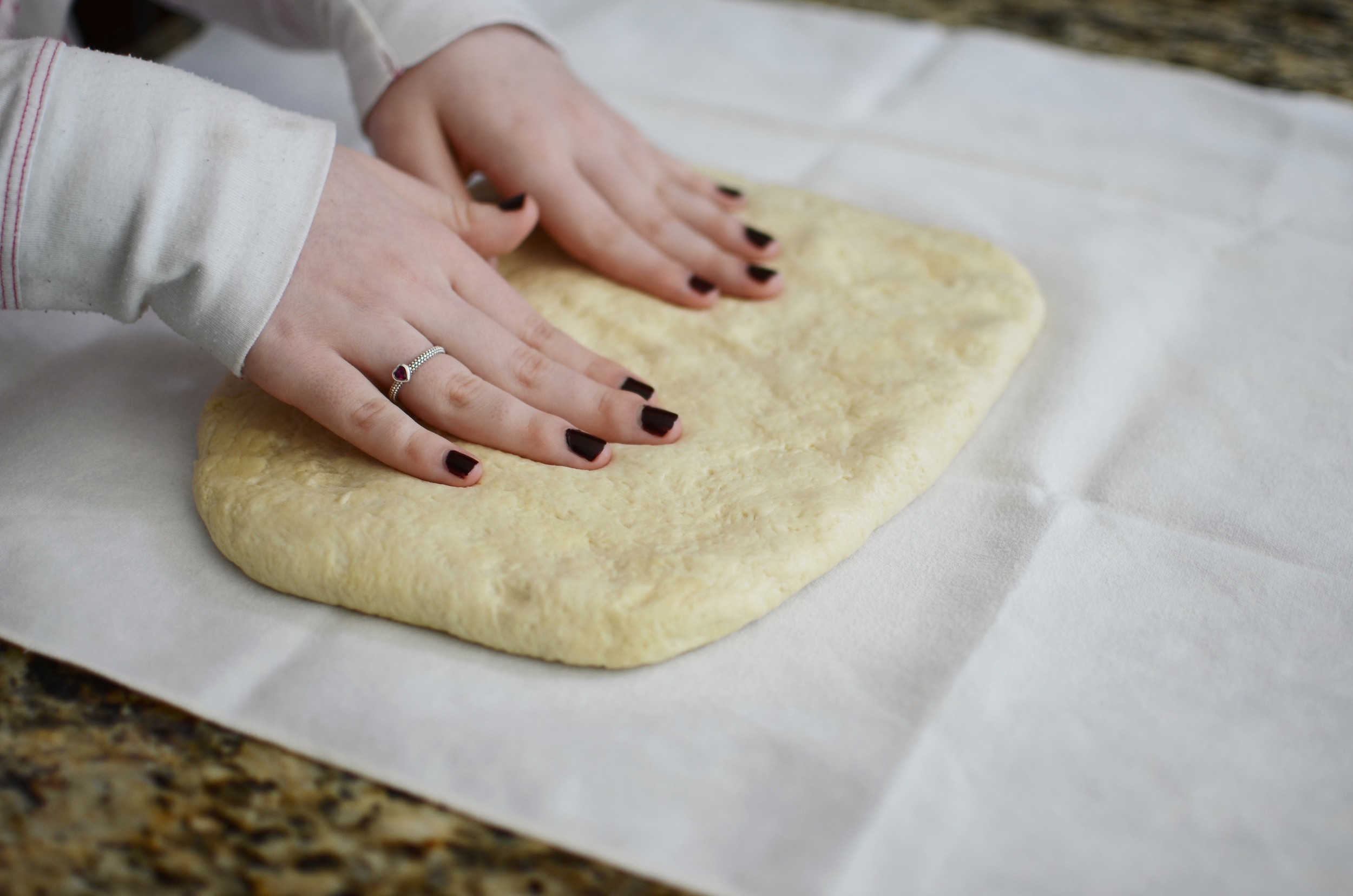 So here we are after what should have been a very short amount of time, but in actuality, we prolonged the process by 4 days. Either way, it is now time to have some fun. The dough is patted out into a rectangle. I like to teach my students to use a pastry cloth when working with bread dough. They're very user- friendly and they really cut down on the chances of incorporating too much flour into the dough. They help contain the mess too.