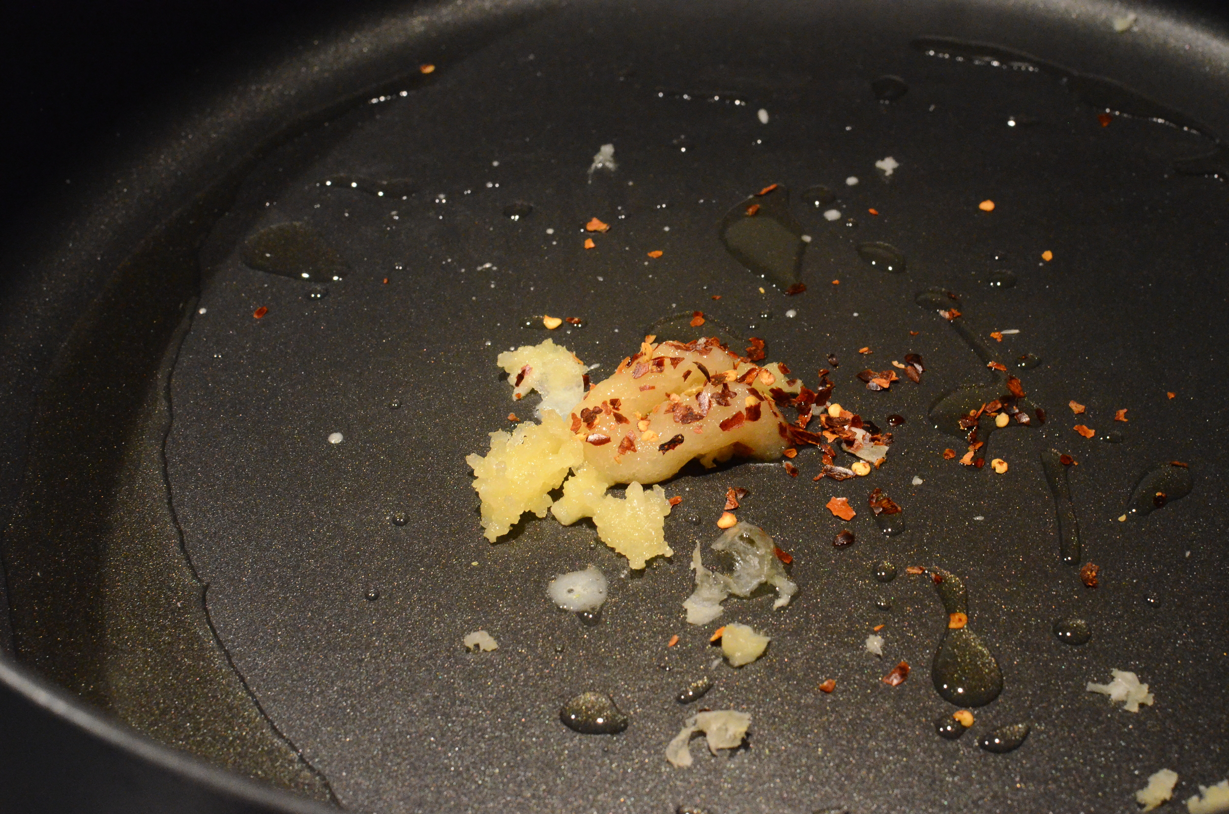 Start by sauteing crushed garlic, ginger paste, and crushed red pepper flakes in a little oil over medium-high heat.