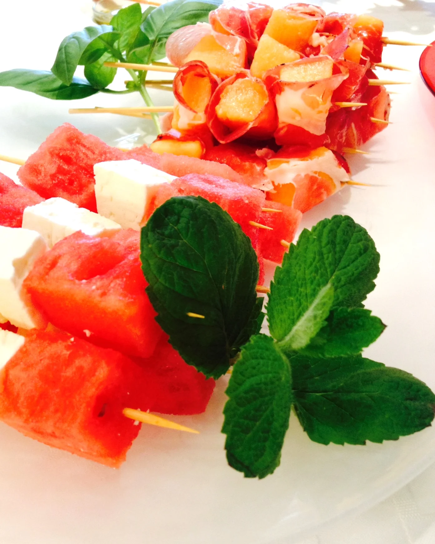 (front) Watermelon and Feta Cheese Skewers with Mint (back) C antelope and Prosciutto Skewers with Basil