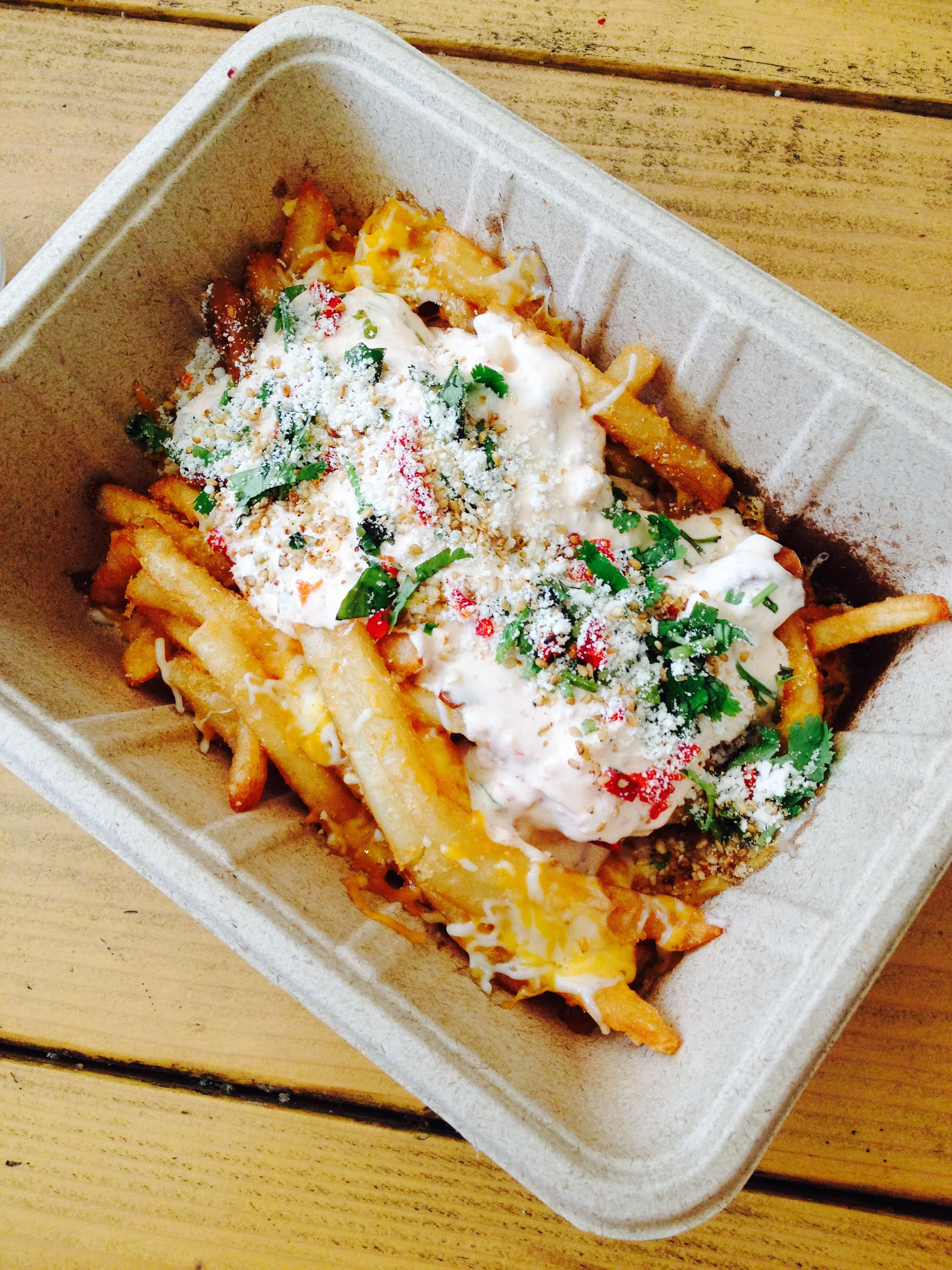 Ooey Gooey Fries - beer-battered with sour cream sambal, monterey jack and cheddar cheese, cotija, chilies, cilantro, and pickled garlic.
