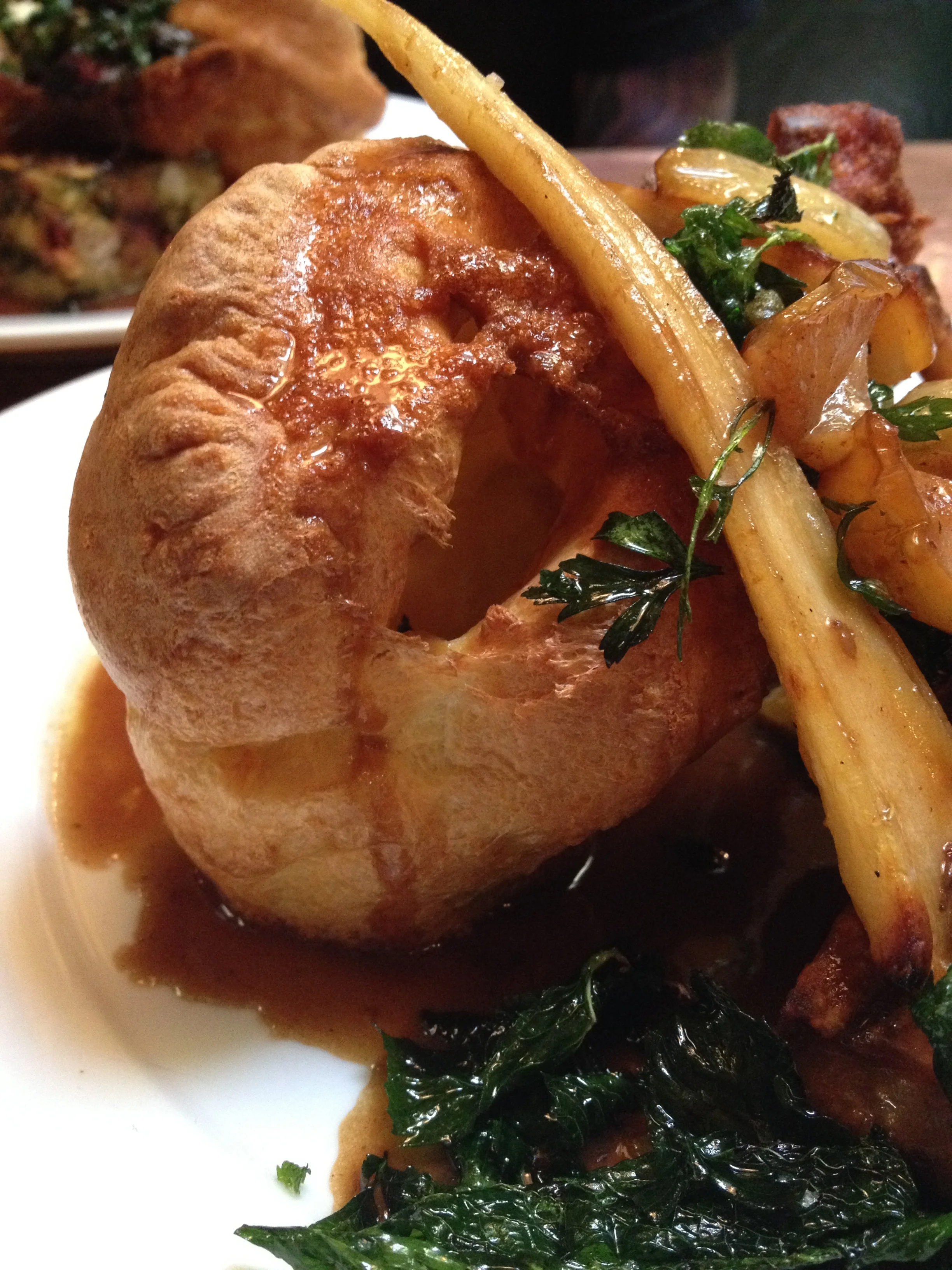 Sunday Roast Slow-Roasted Pork Belly with Caramelized Apples & Parsnips, accompanied by stuffing, roasted potatoes, Yorkshire pudding, and gravy.