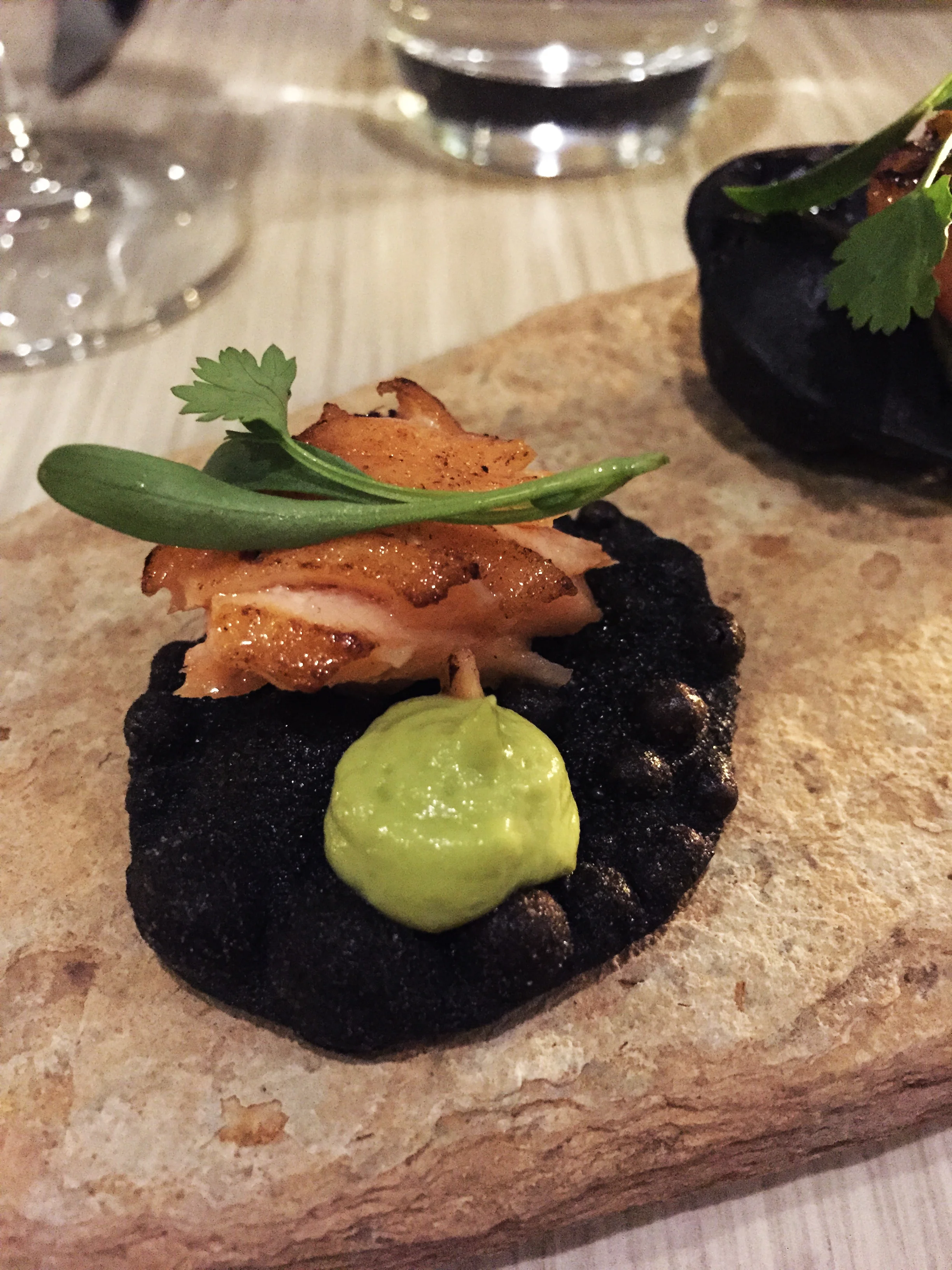 Salmon Tataki on squid ink tostada amuse bouche.