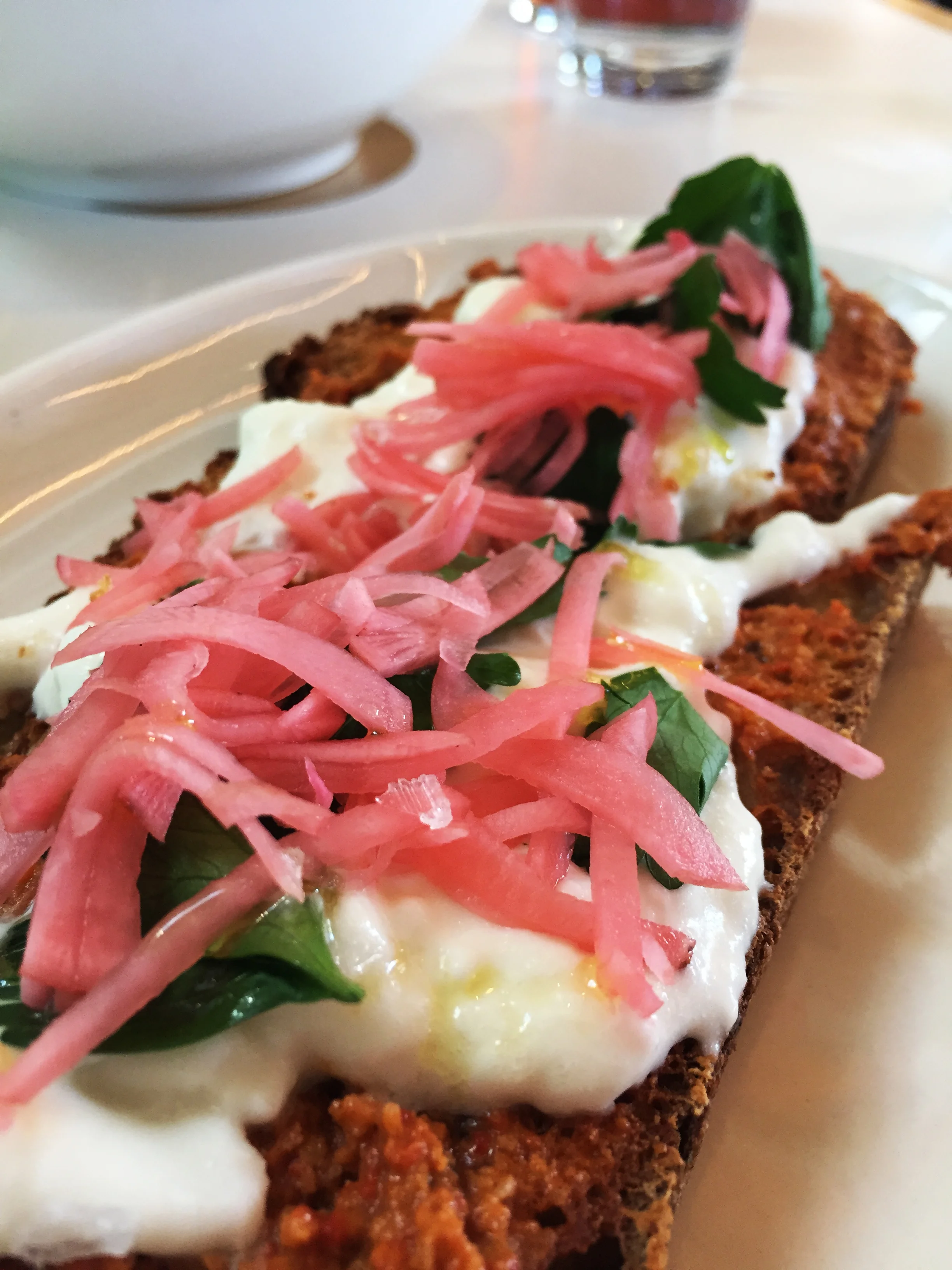 Burrata Toasty with with walnut muhammara , pickled radish, and parsley.