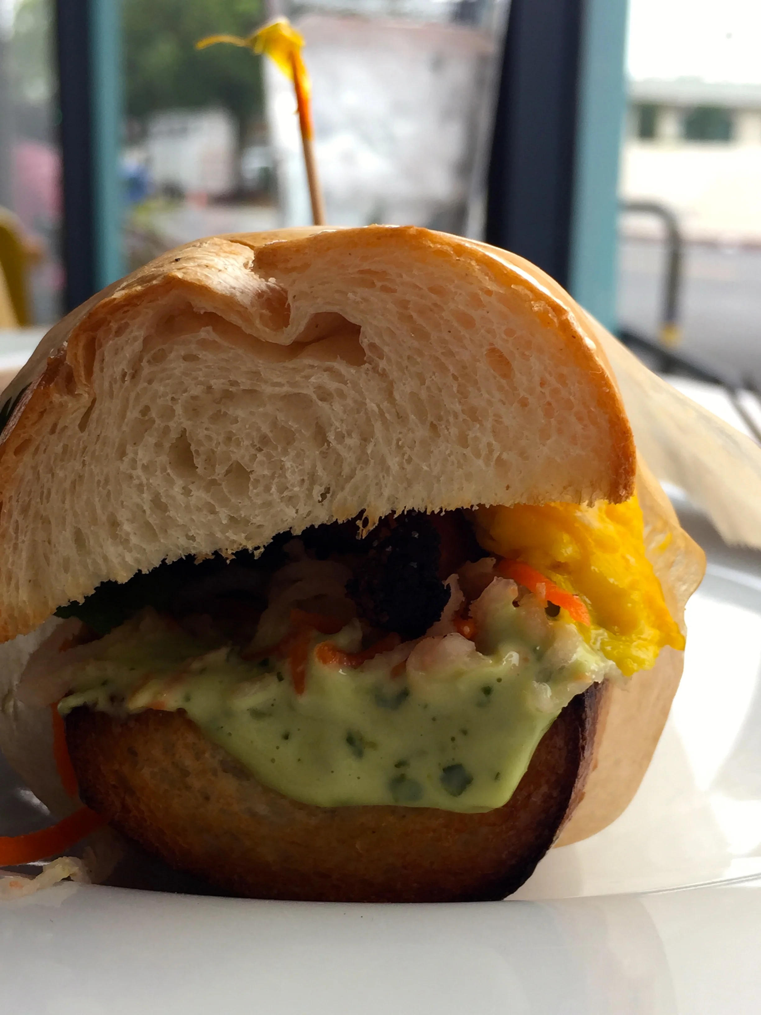 Breakfast Banh Mi with scrambled egg, bacon, pickled daikon & carrots, cilantro-maggi mayo.