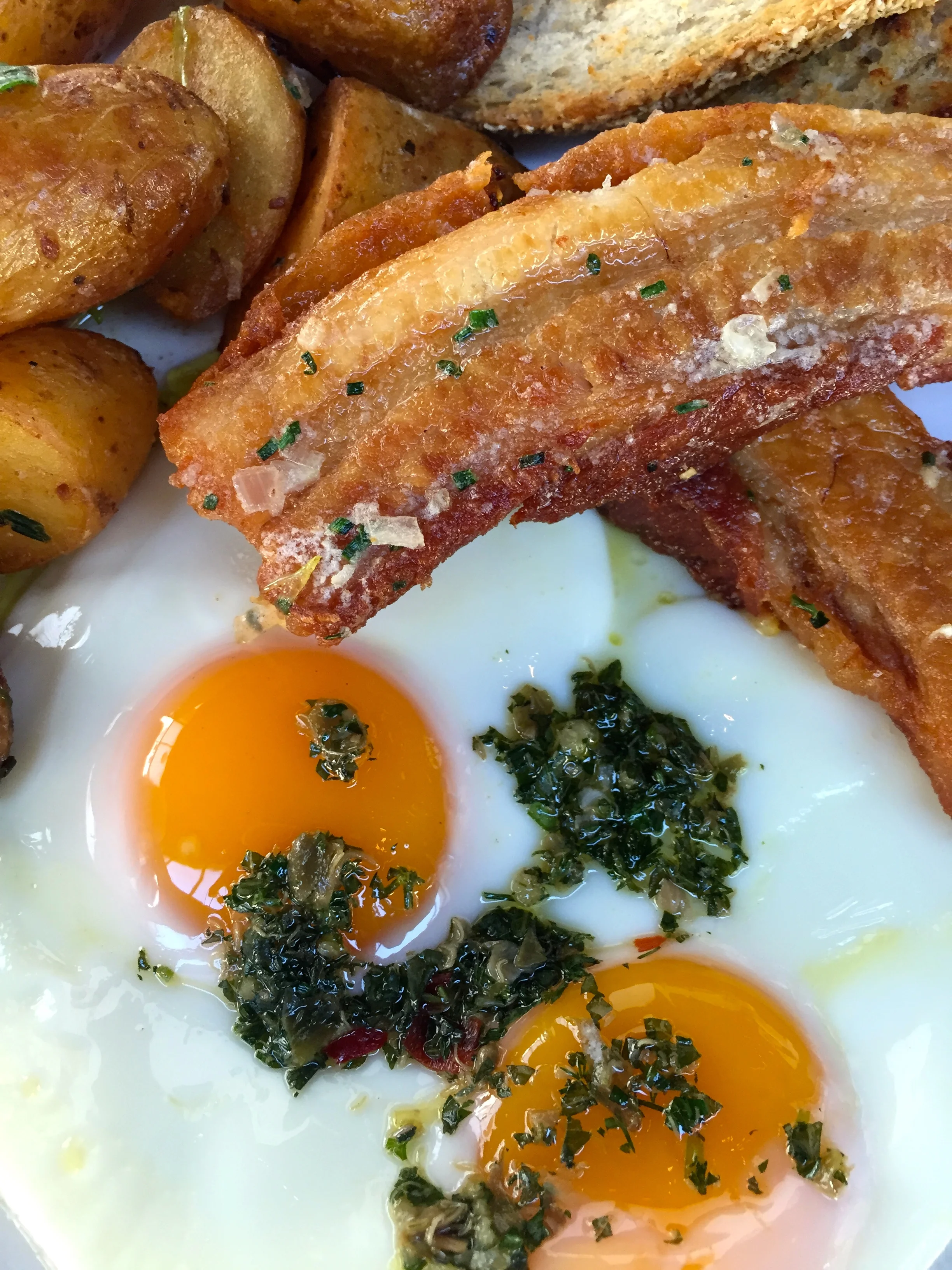 Breakfast Combo with fried eggs, duck fat potatoes, crispy pork belly, and salsa verde.