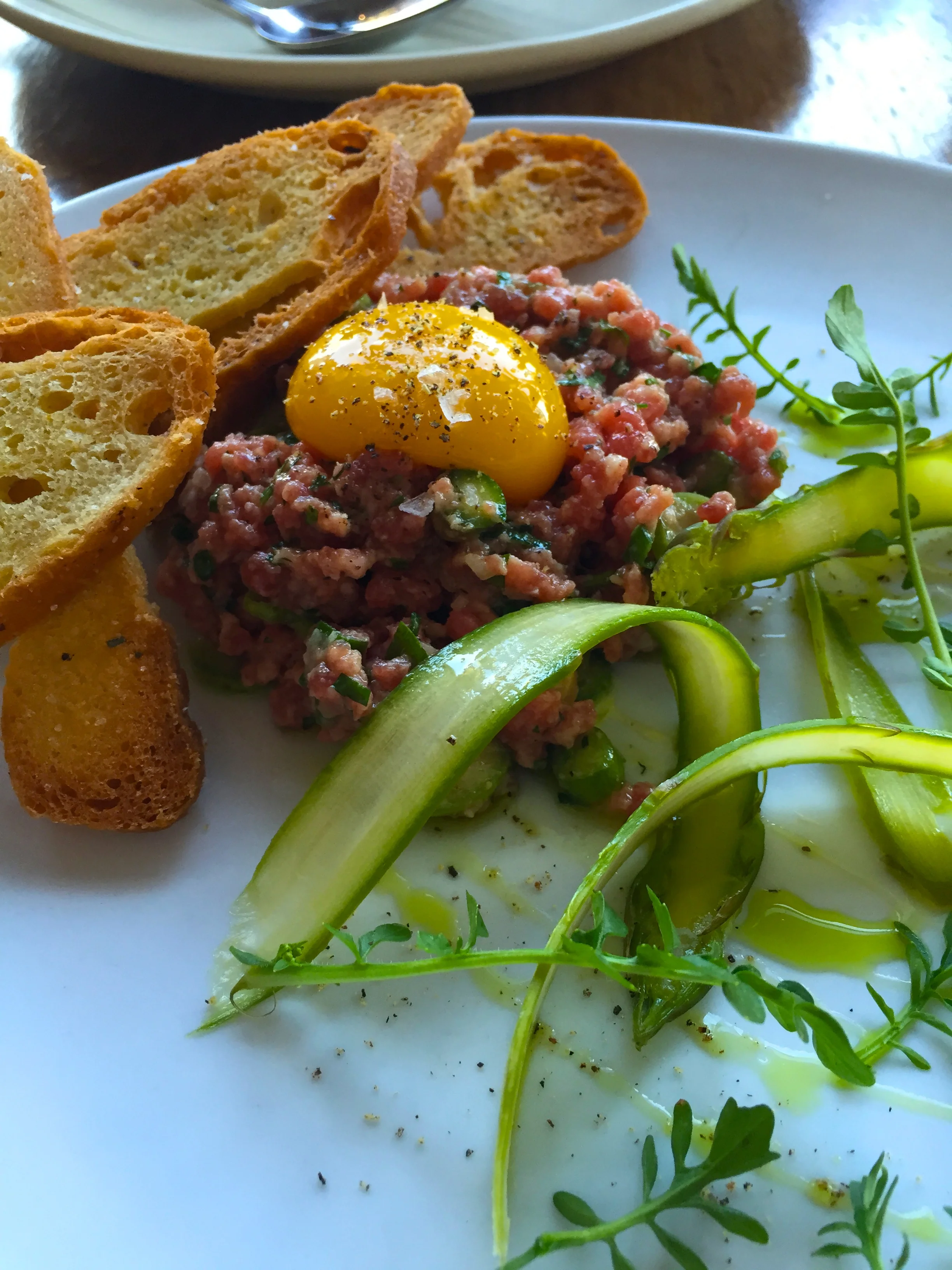 Prime Beef & Asparagus Tartare with white soy and yuzu dressing, egg yolk, garlic, chive, and jaime farms watercress.