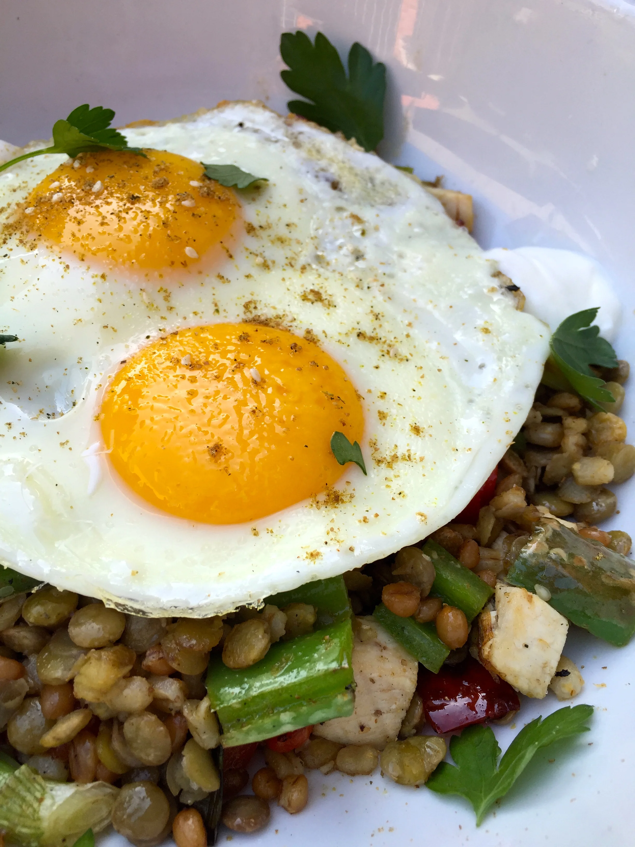 Jerusalem bowl with warm wheat berries, lentils and barley, Zahtar chicken, roasted green chiles, and two fried eggs.