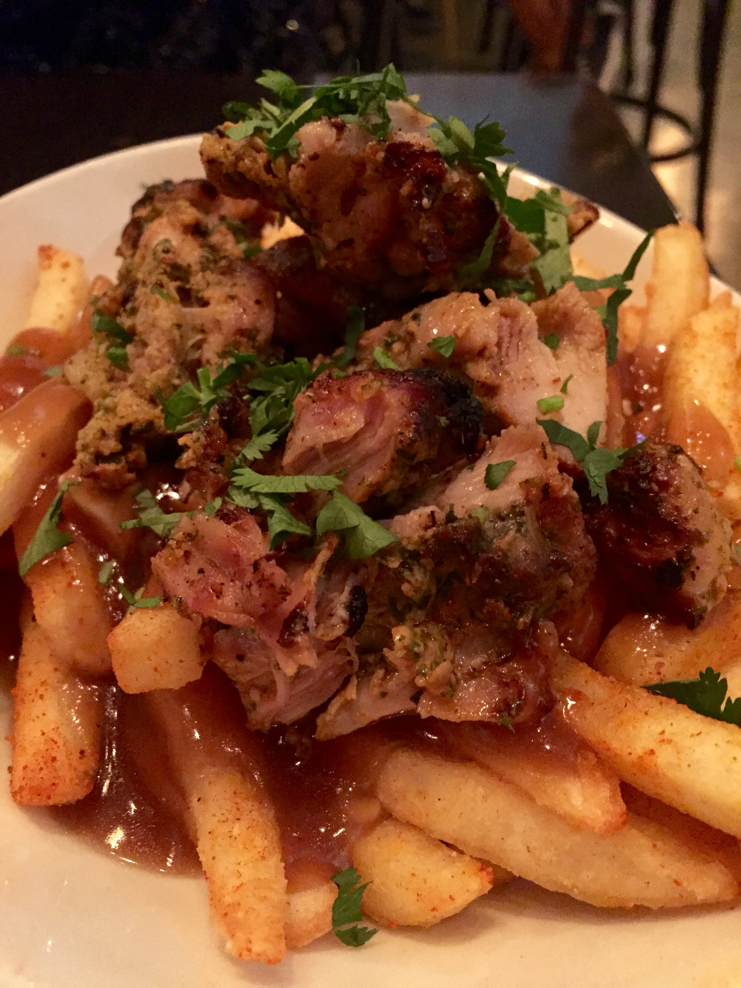 Chicken Tikka Poutine - masala fries topped with cheese curds, doused in piping hot beef gravy, all topped with tandoori chicken tikka and cilantro.