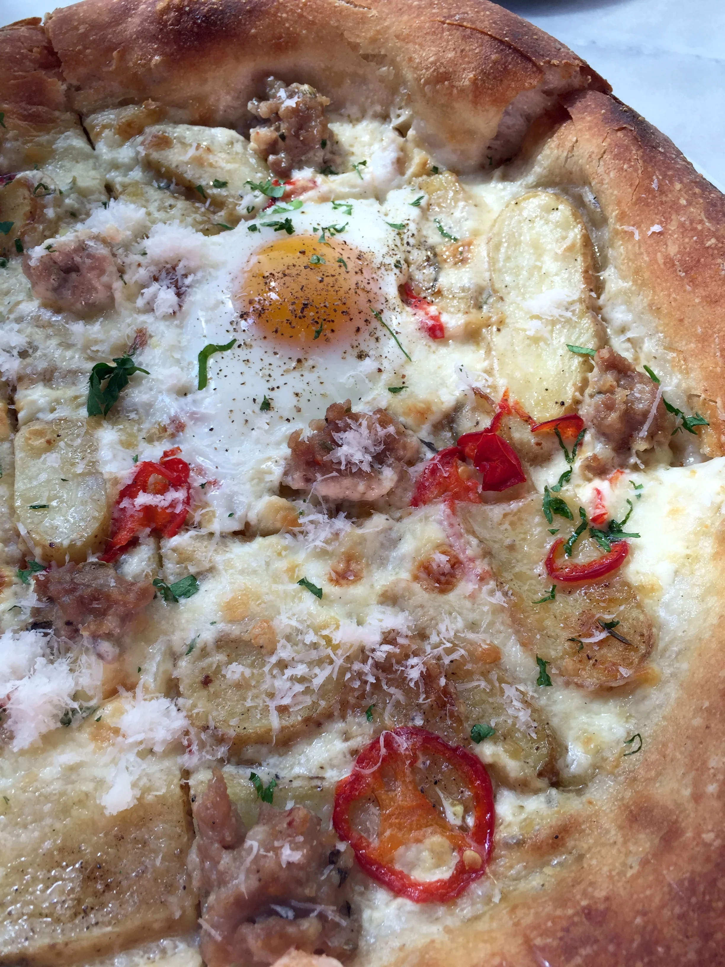 BREAKFAST PIZZA - house sausage, potatoes, pickled chile, rosemary cream, and a farm egg.