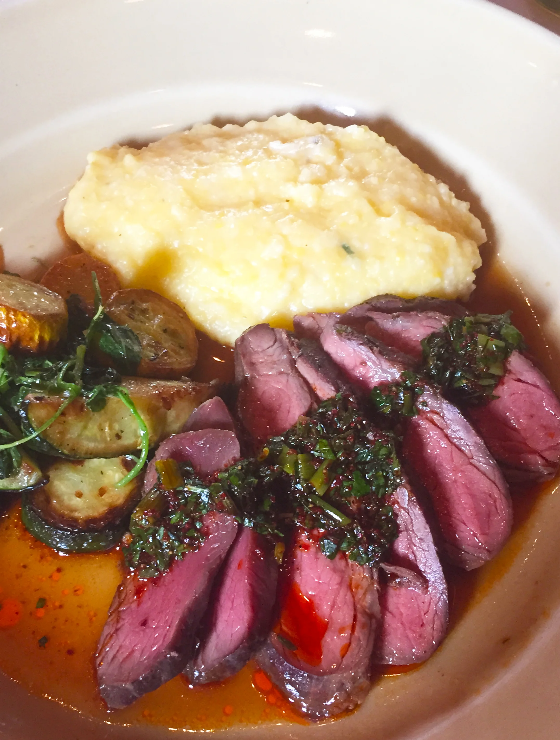 Grilled Stemple Creek Ranch sirloin with polenta, zucchini, scallions, and chimichurri sauce.