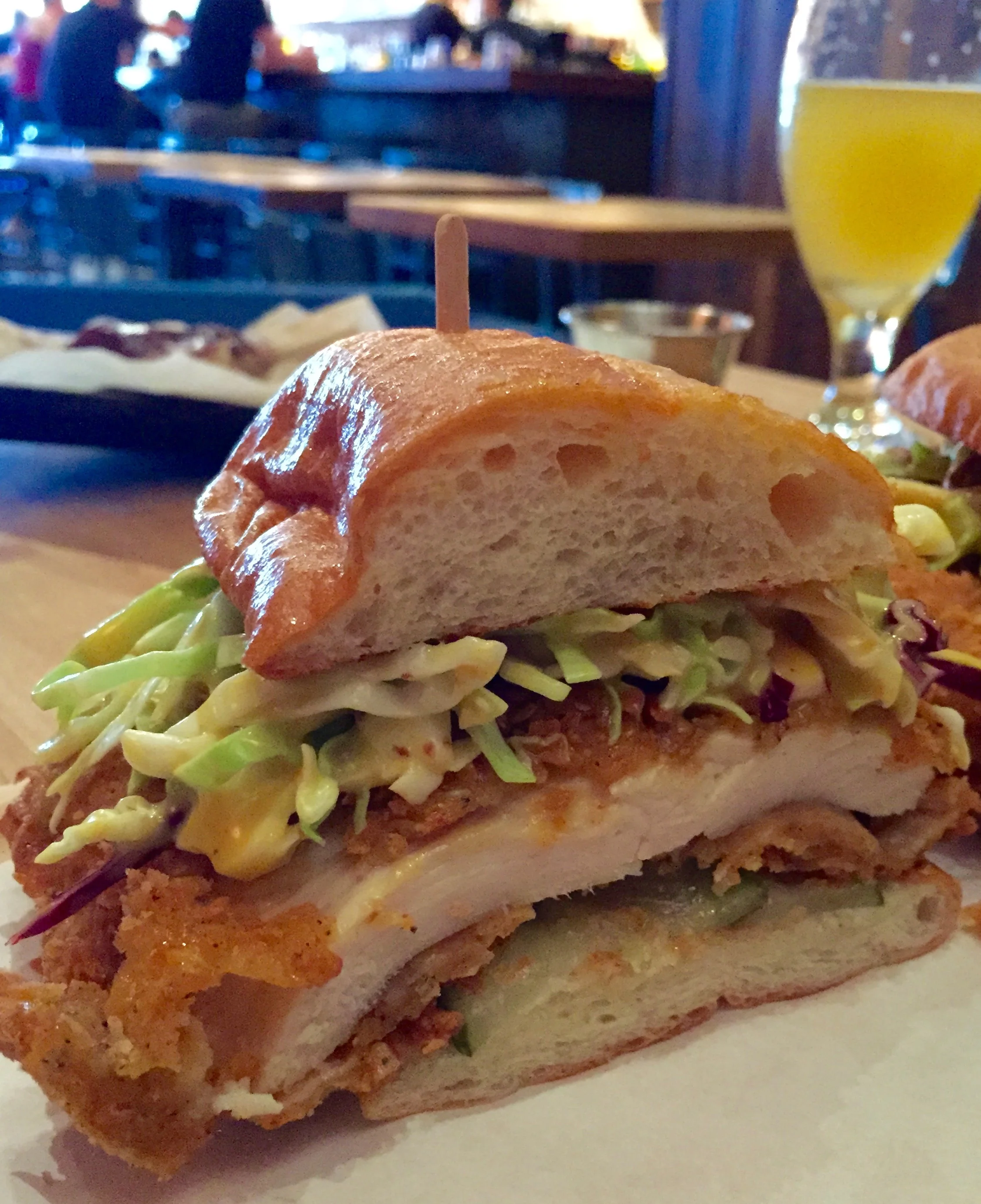 Crispy Chicken Sandwich with chicken breast, cabbage slaw, dill pickles on a sweet roll.