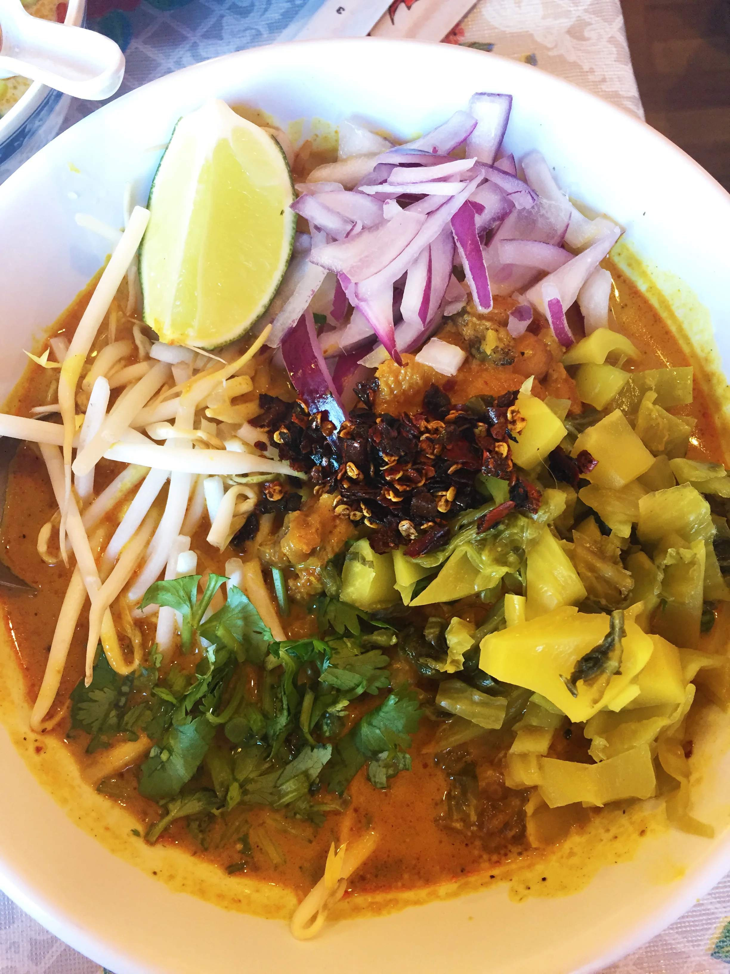 Khao Soi Gai - mae sai curried noodles with chicken and homemade nam prik khao soi, topped with bean sprouts, red onion, pickled mustard greens, cilantro, and chile jam.