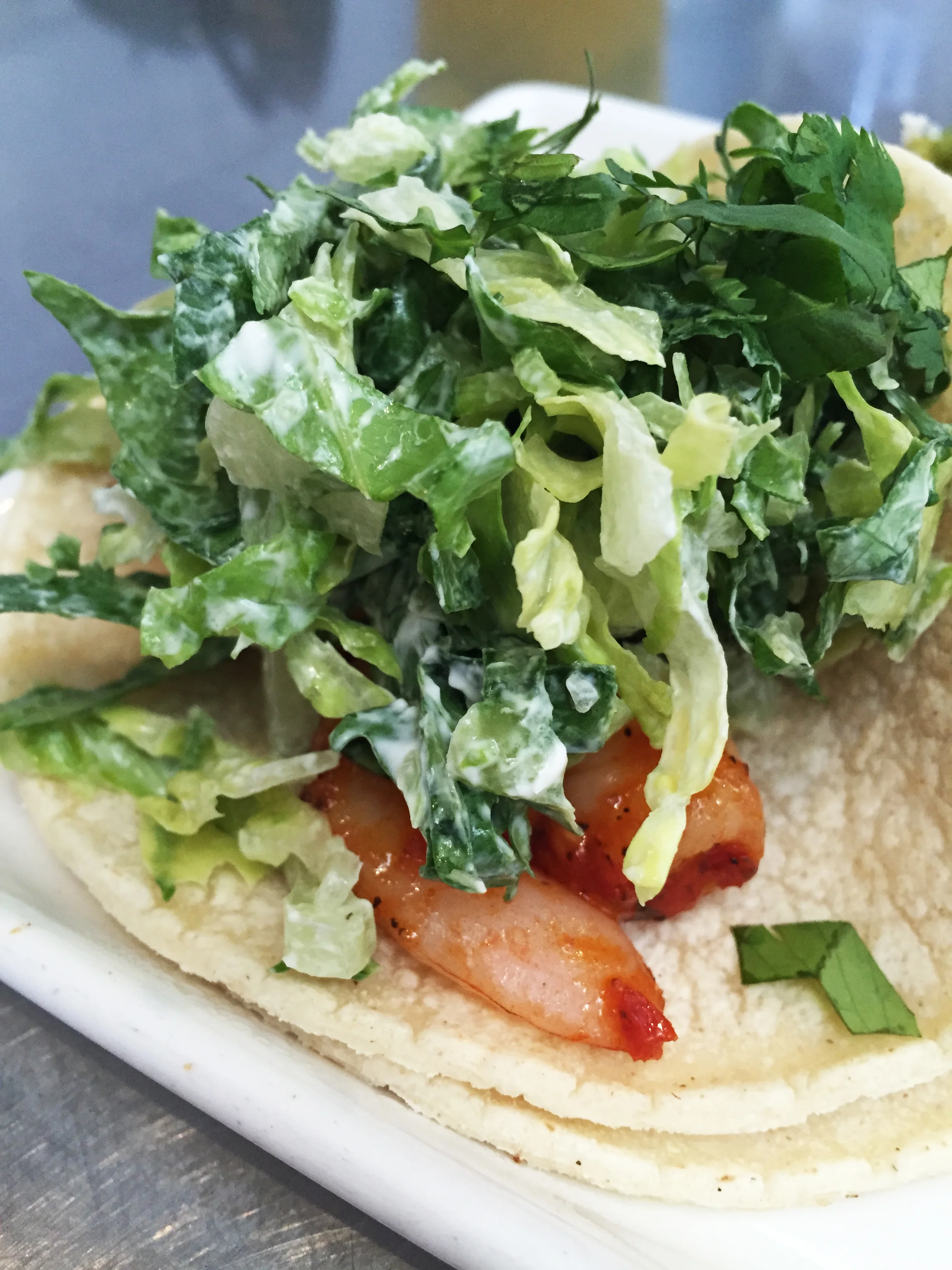 Blazin' Shrimp Taco with spicy Singaporean-style shrimp, sour cream, salad, and cilantro.