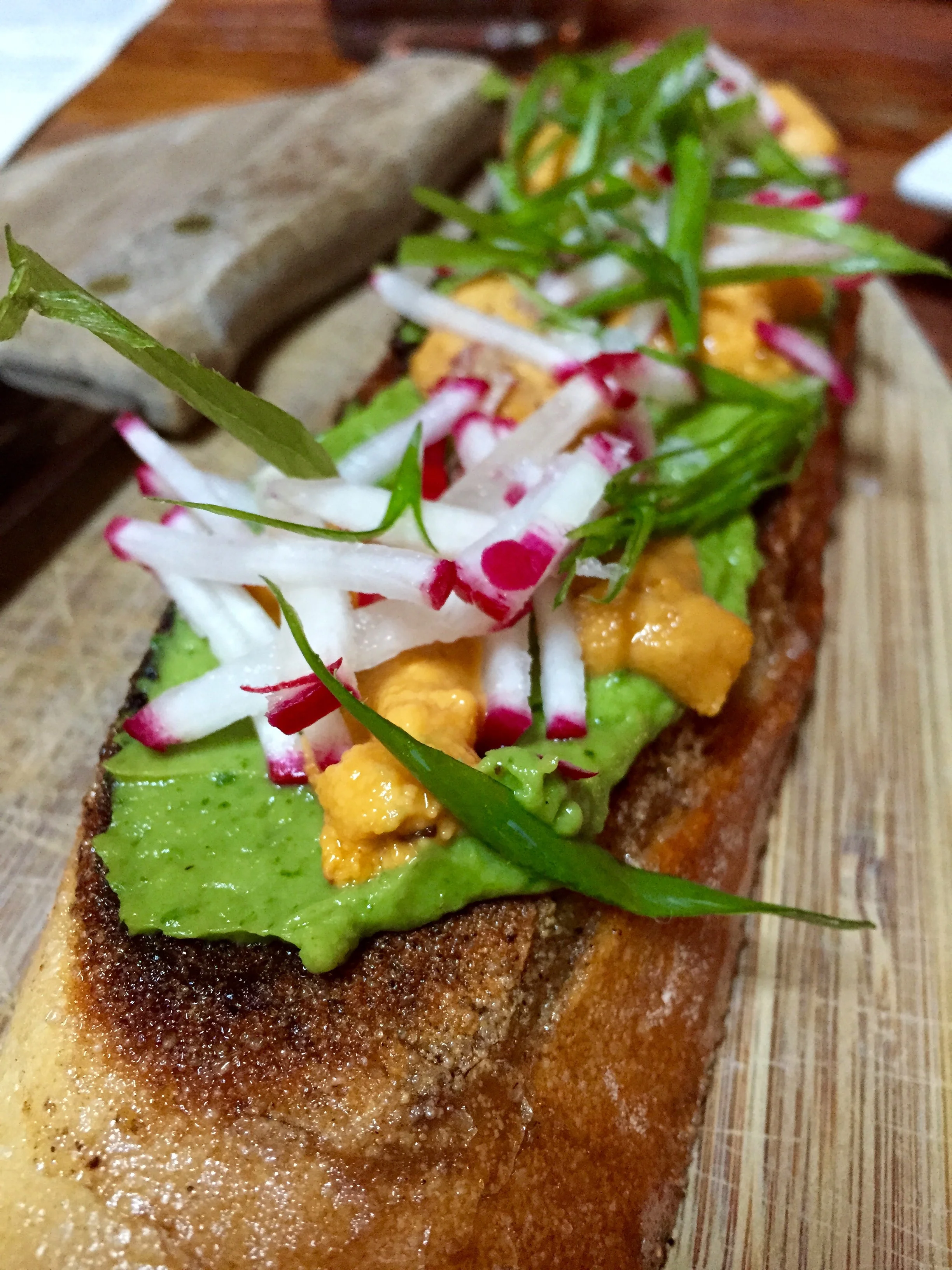 Sea Urchin Toast with avocado mousse, radish, and scallions.