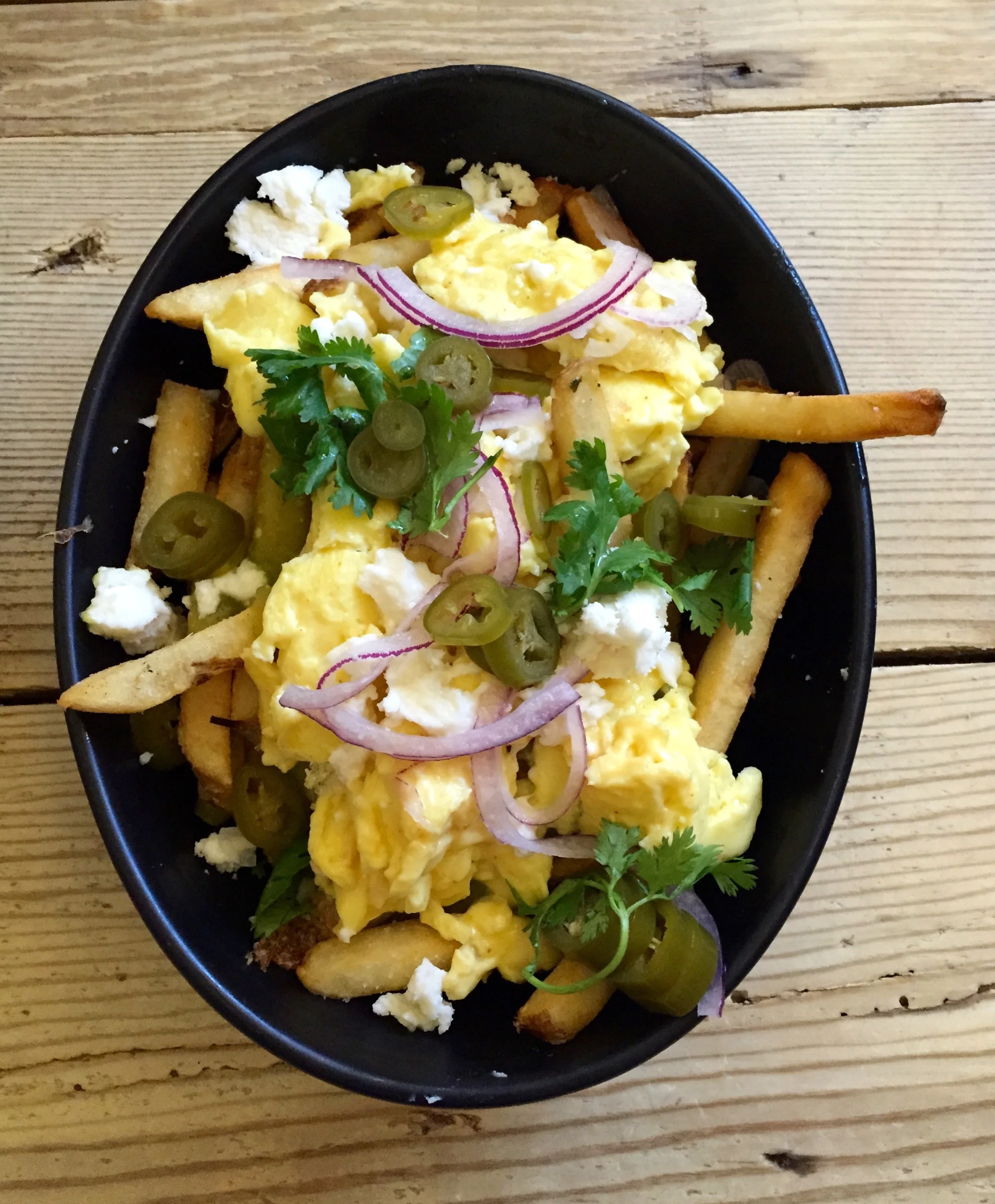 Chilaquiles Poutine with salsa verde, pickled serranos, queso fresco, and scrambled eggs.