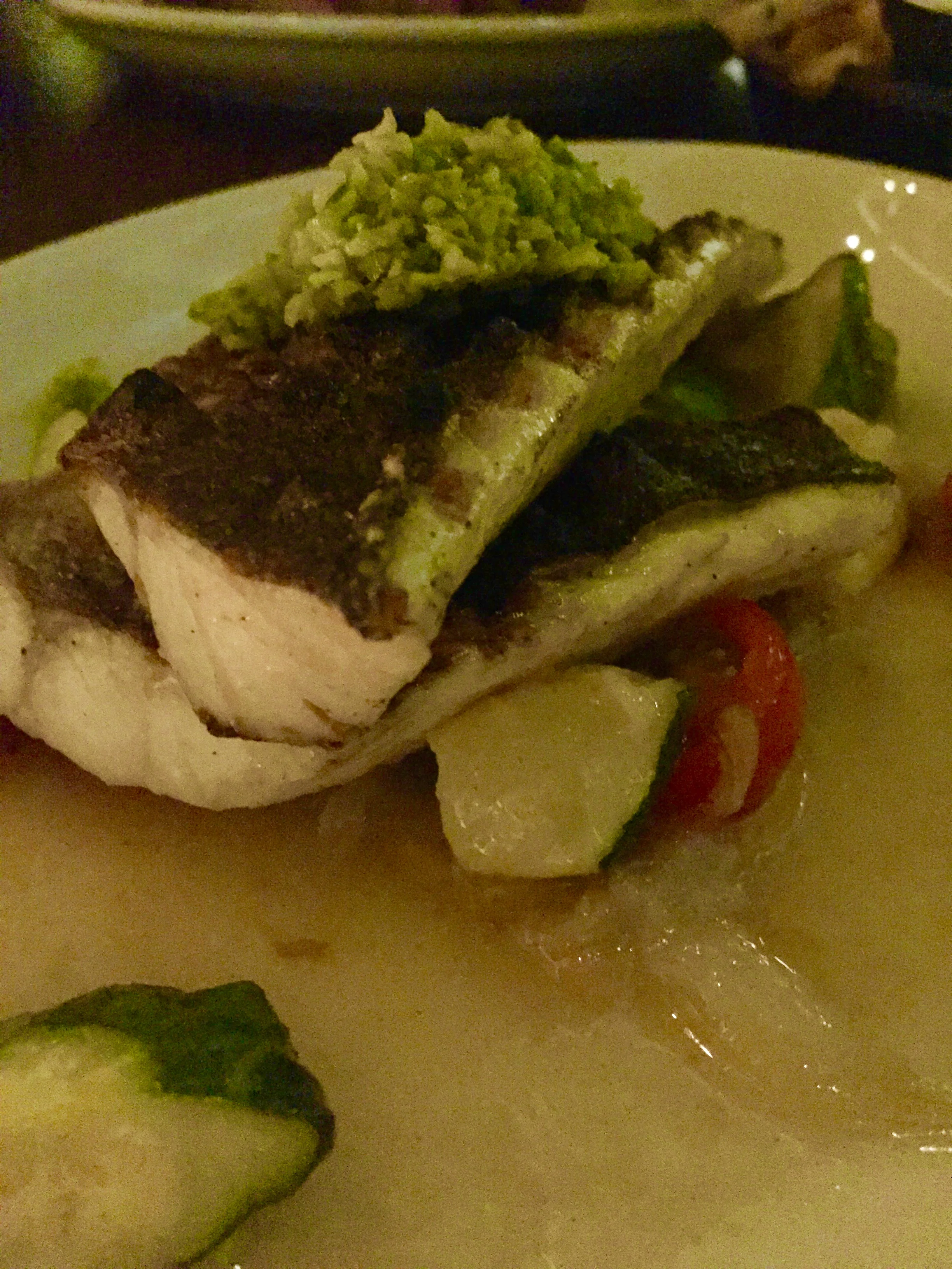 Oak-grilled branzino with cherry tomato, spring onion, summer squash, lemon confit, and green olive tapenade.